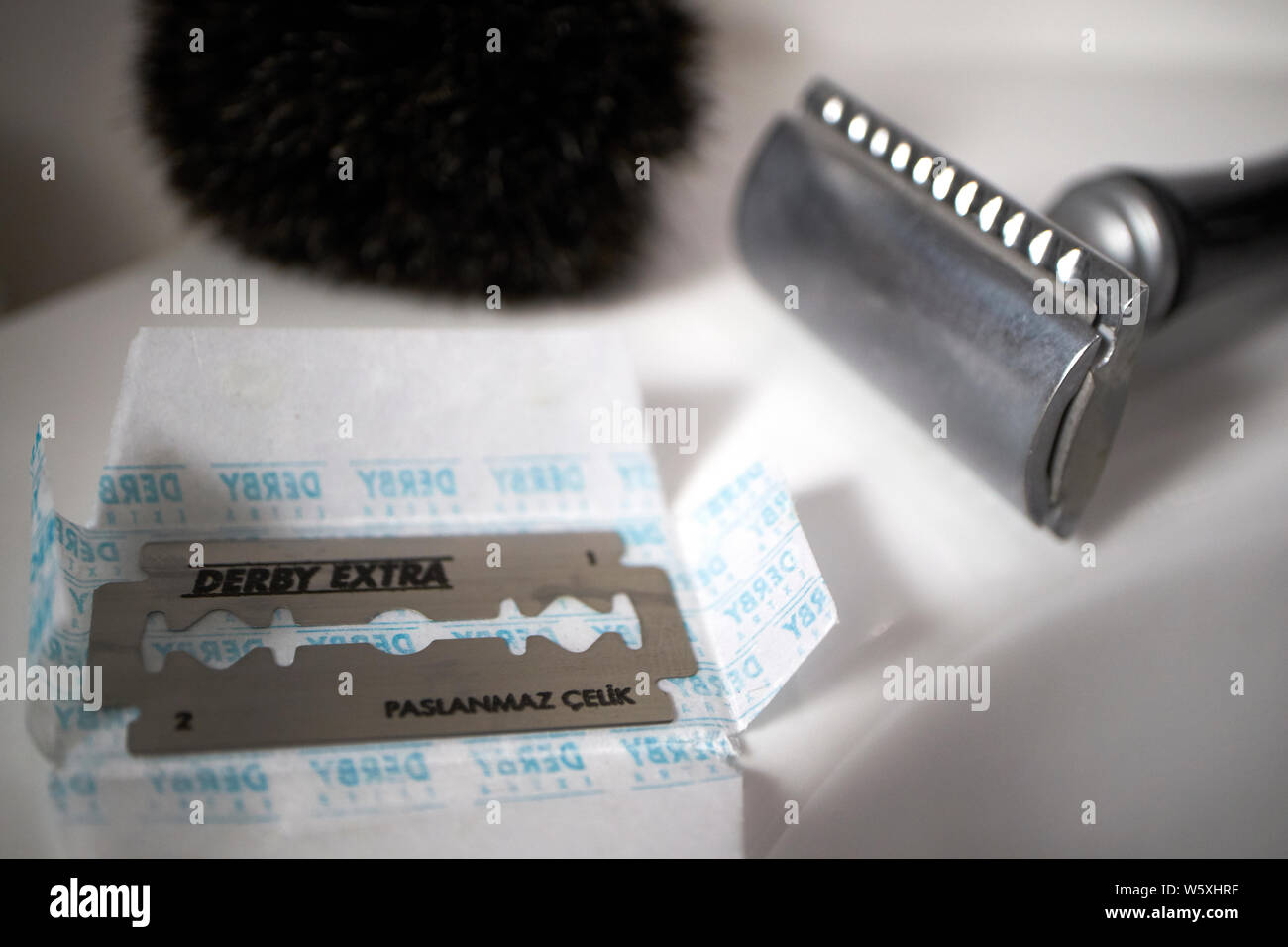 new razor blade with mens safety razor and badger shaving brush in a bathroom Stock Photo