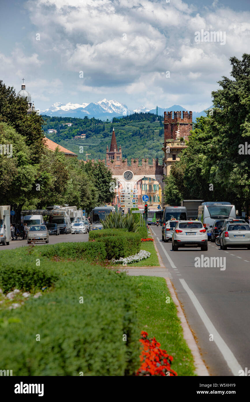 Traffic on Verona's Corso Nuova heads towards the Portini della Bra, the 16th century city gateway. Little Dolomite mountains are in the distance. Stock Photo