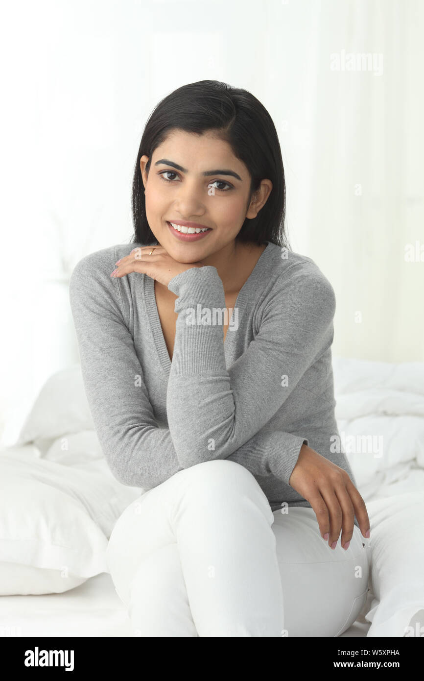 Portrait of a woman sitting on the bed smiling Stock Photo - Alamy