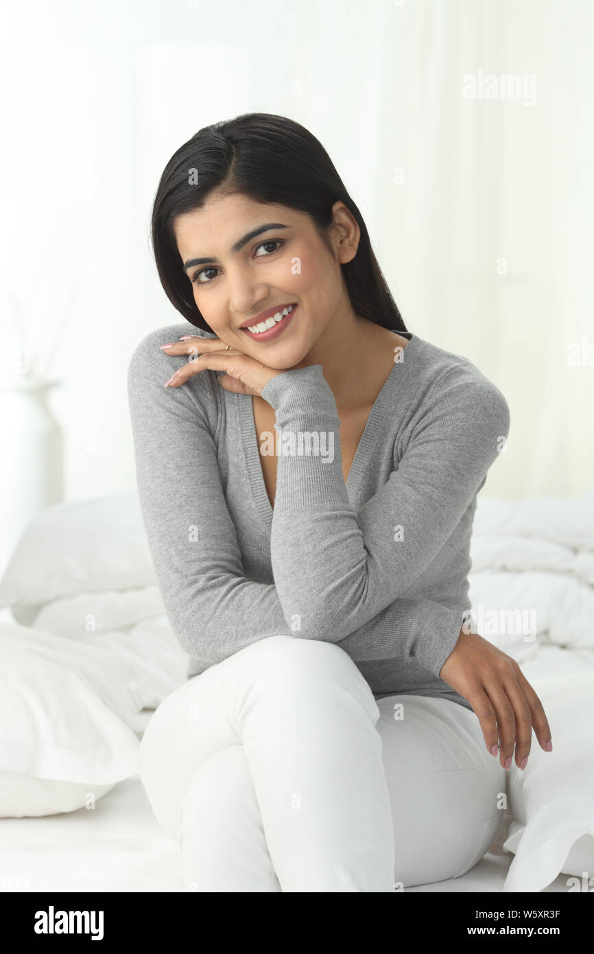 Portrait of a woman sitting on the bed smiling Stock Photo - Alamy