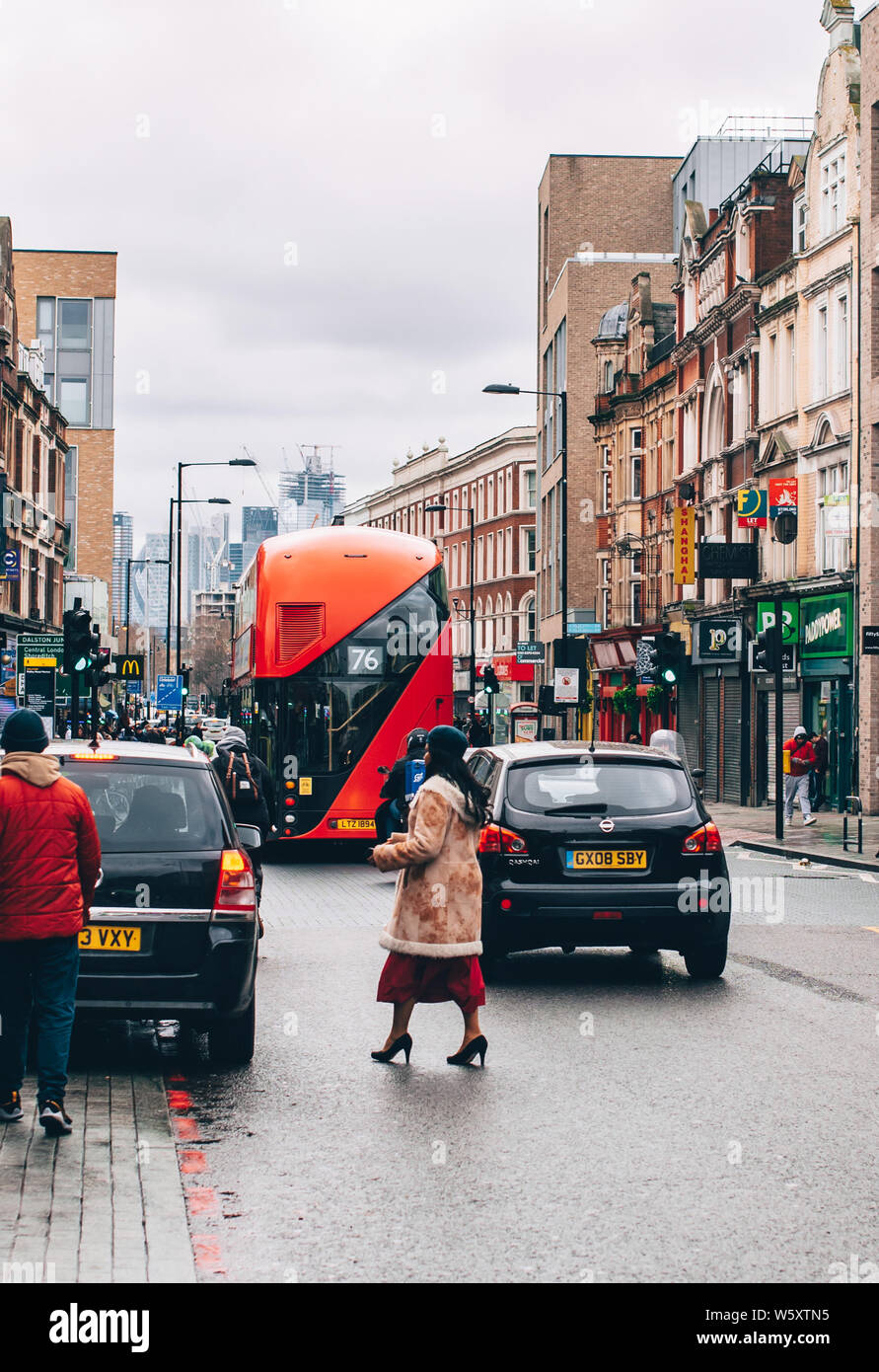 A stylish woman crosses the road in Dalston, East London during winter. Stock Photo