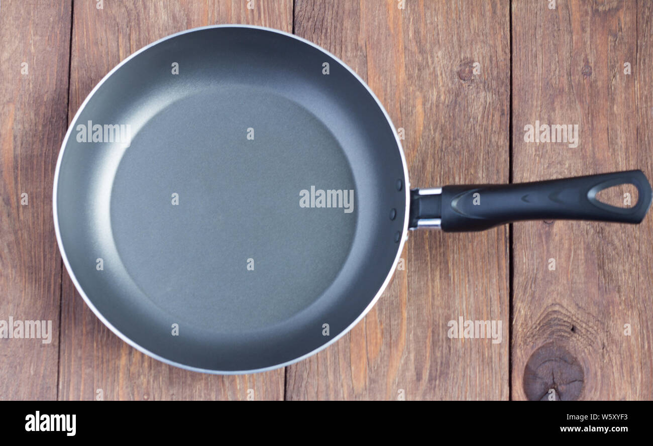 empty frying pan with non-stick coating on wooden background Stock Photo