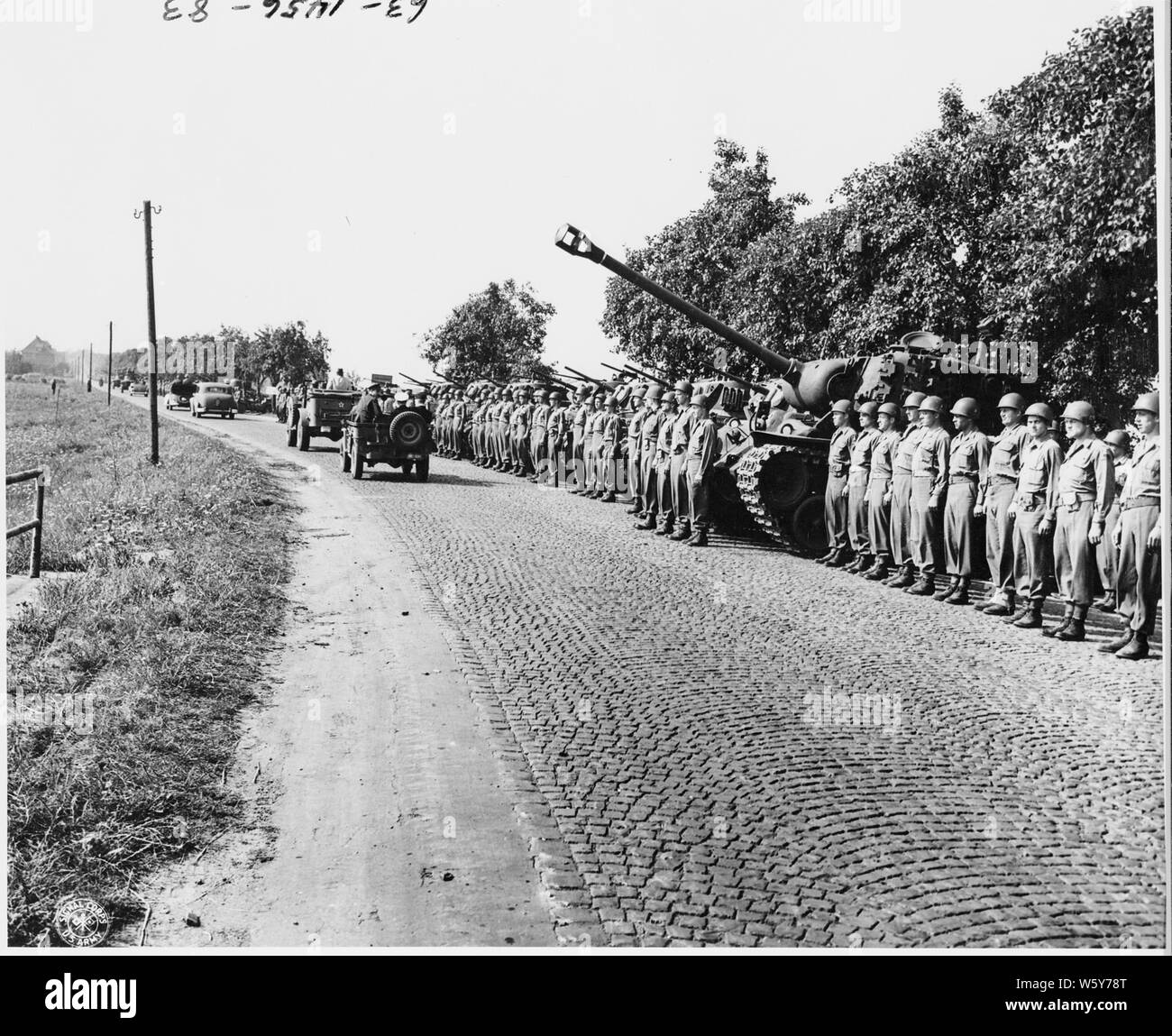Tanks and men of the 3rd Armored Division, 23rd Corps, Seventh Army, line a highway as President Harry S. Truman passes by in his sedan during his visit to inspect troops at Neuisenburg, Germany. President Truman has just left the Potsdam Conference for a quick tour of the American occupied area. Stock Photo