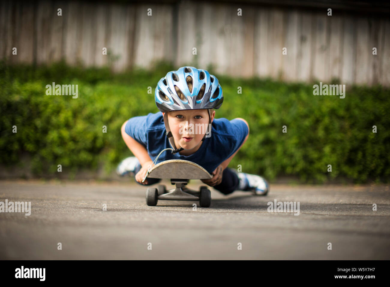 Portrait of a young boy lying down on a skateboard in the driveway Stock  Photo - Alamy