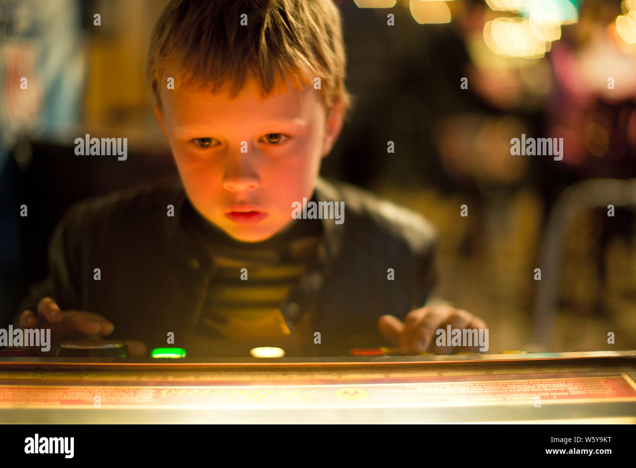 Young boy looking at an arcade game. Stock Photo
