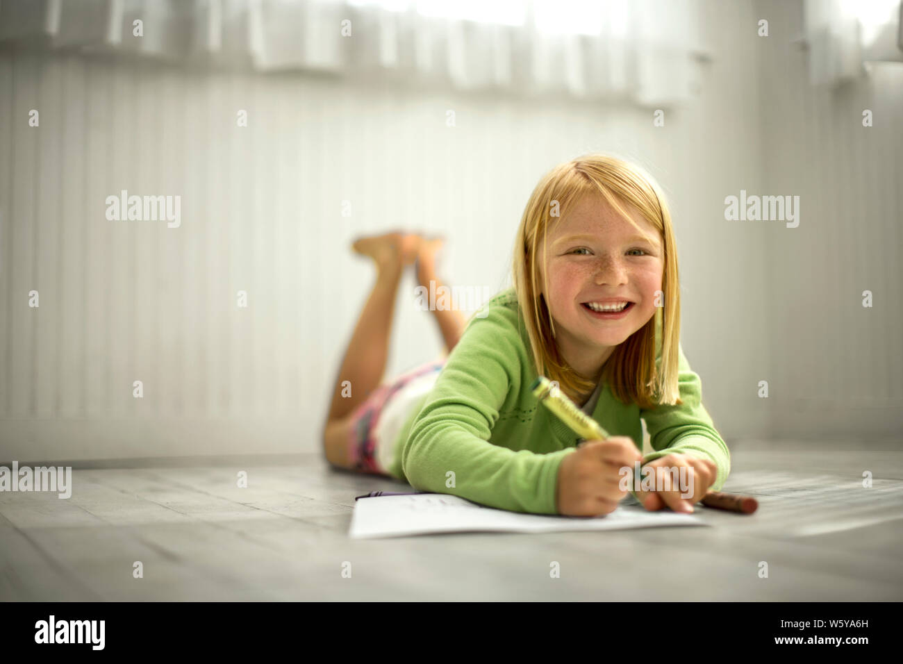 Portrait of a smiling young girl coloring with crayons Stock Photo - Alamy