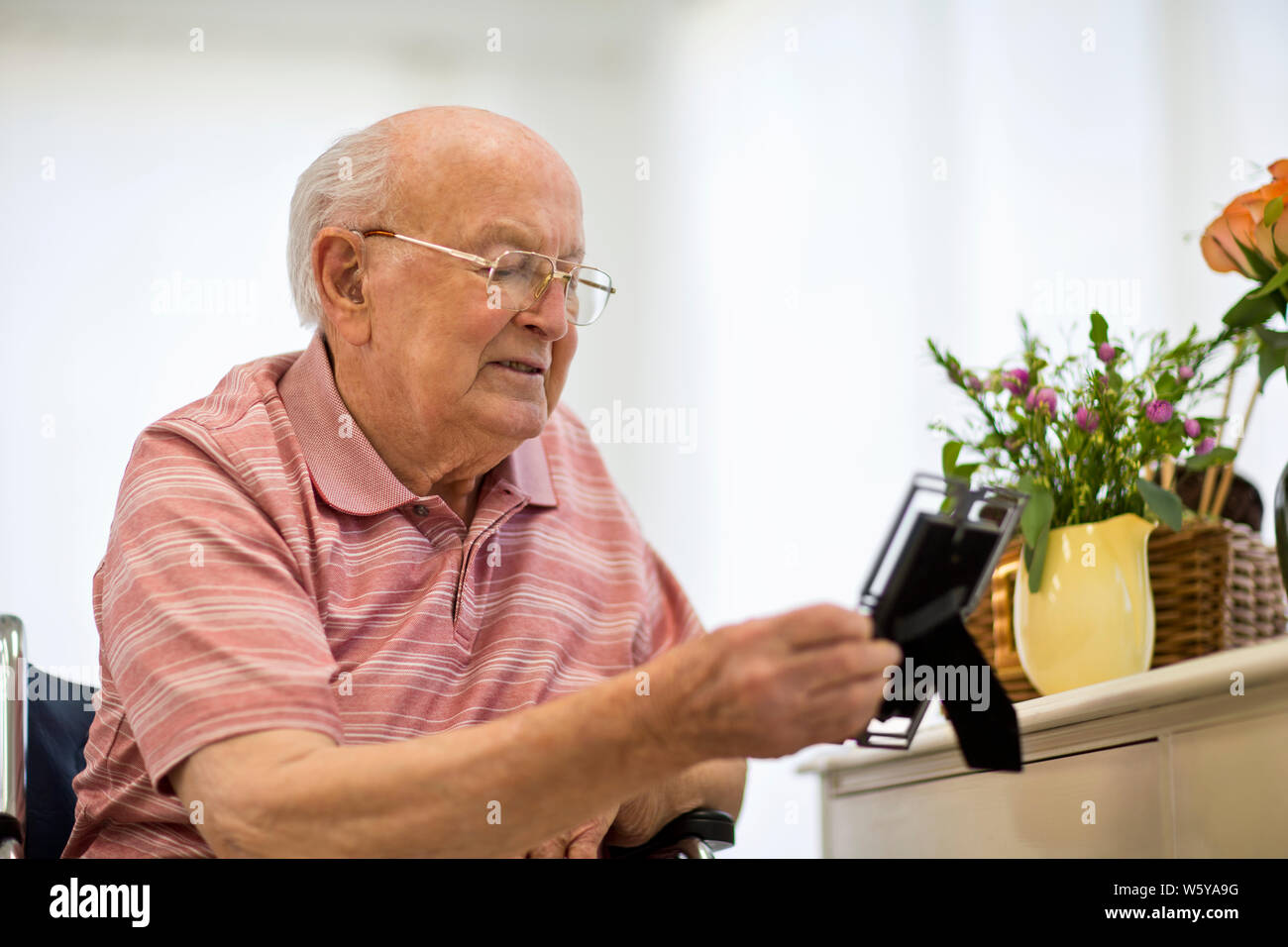 Senior man looking at a picture frame on his bedside table. Stock Photo