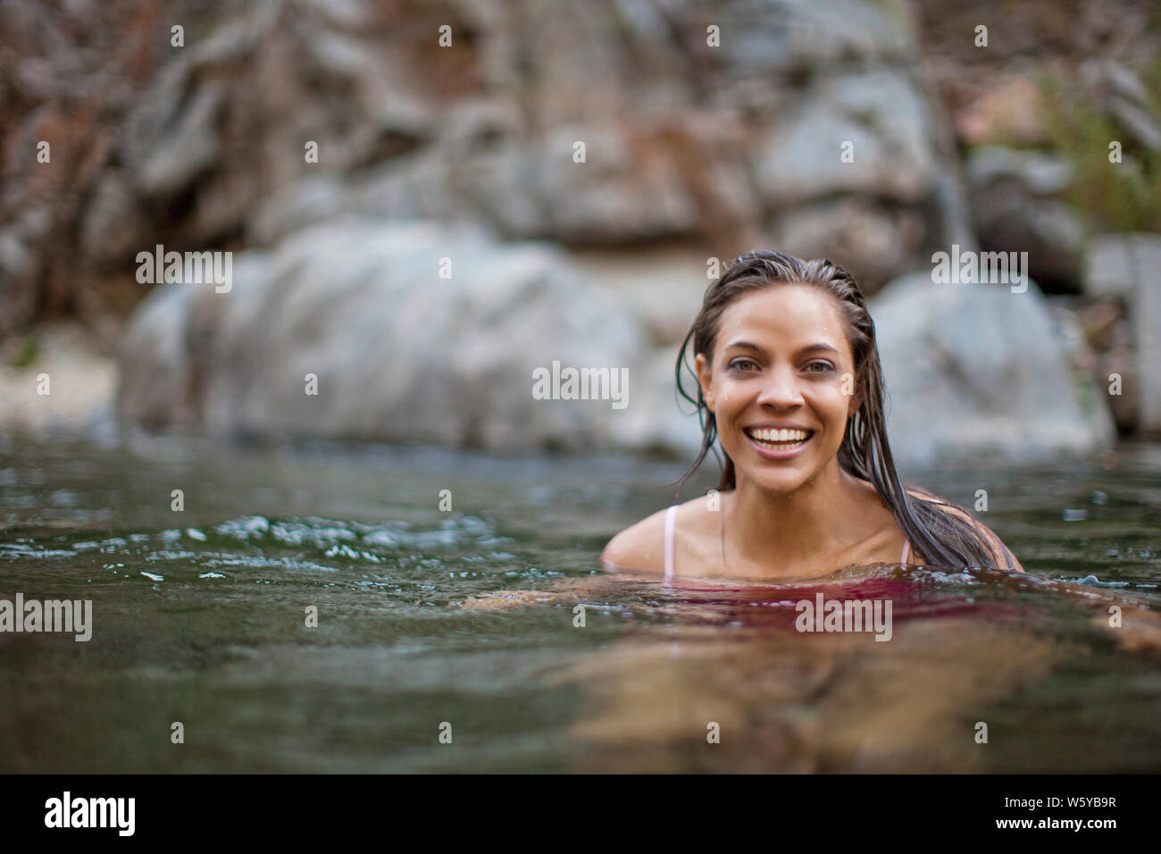 Portrait of a smiling young woman swimming in a river Stock Photo - Alamy