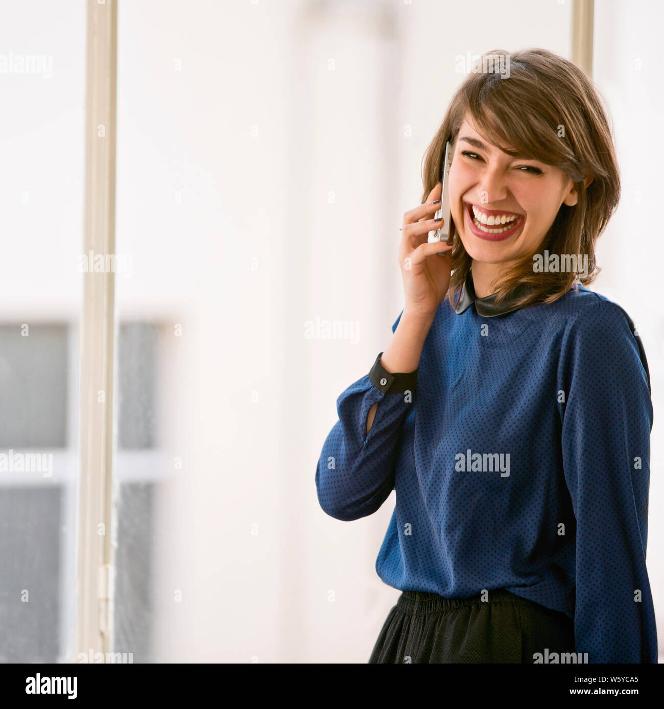 Happy young businesswoman smiles while talking on a cell phone. Stock Photo
