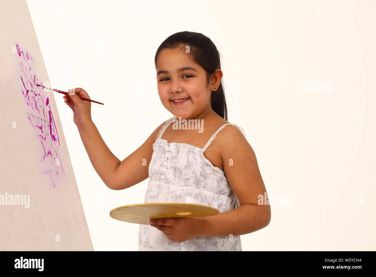 Girl painting on easel and smiling Stock Photo - Alamy