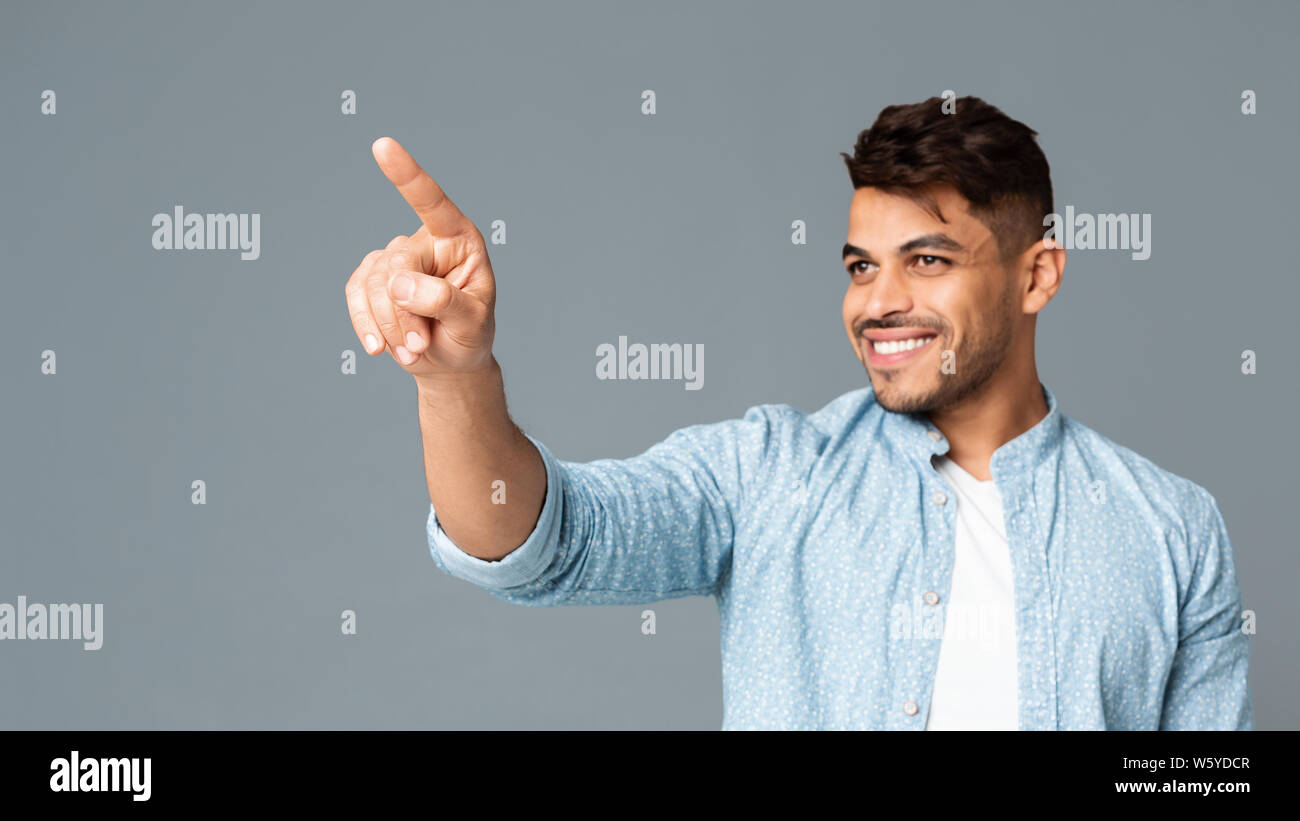 Cheerful Hispanic Man Touching Invisible Screen Interface Stock Photo