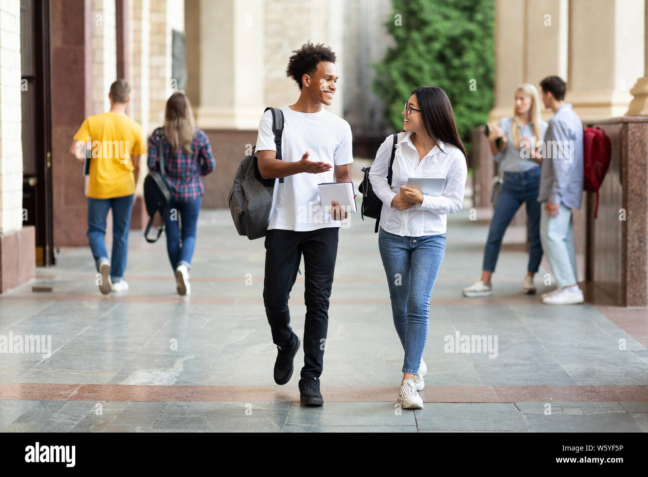Happy diverse students walking in college campus Stock Photo