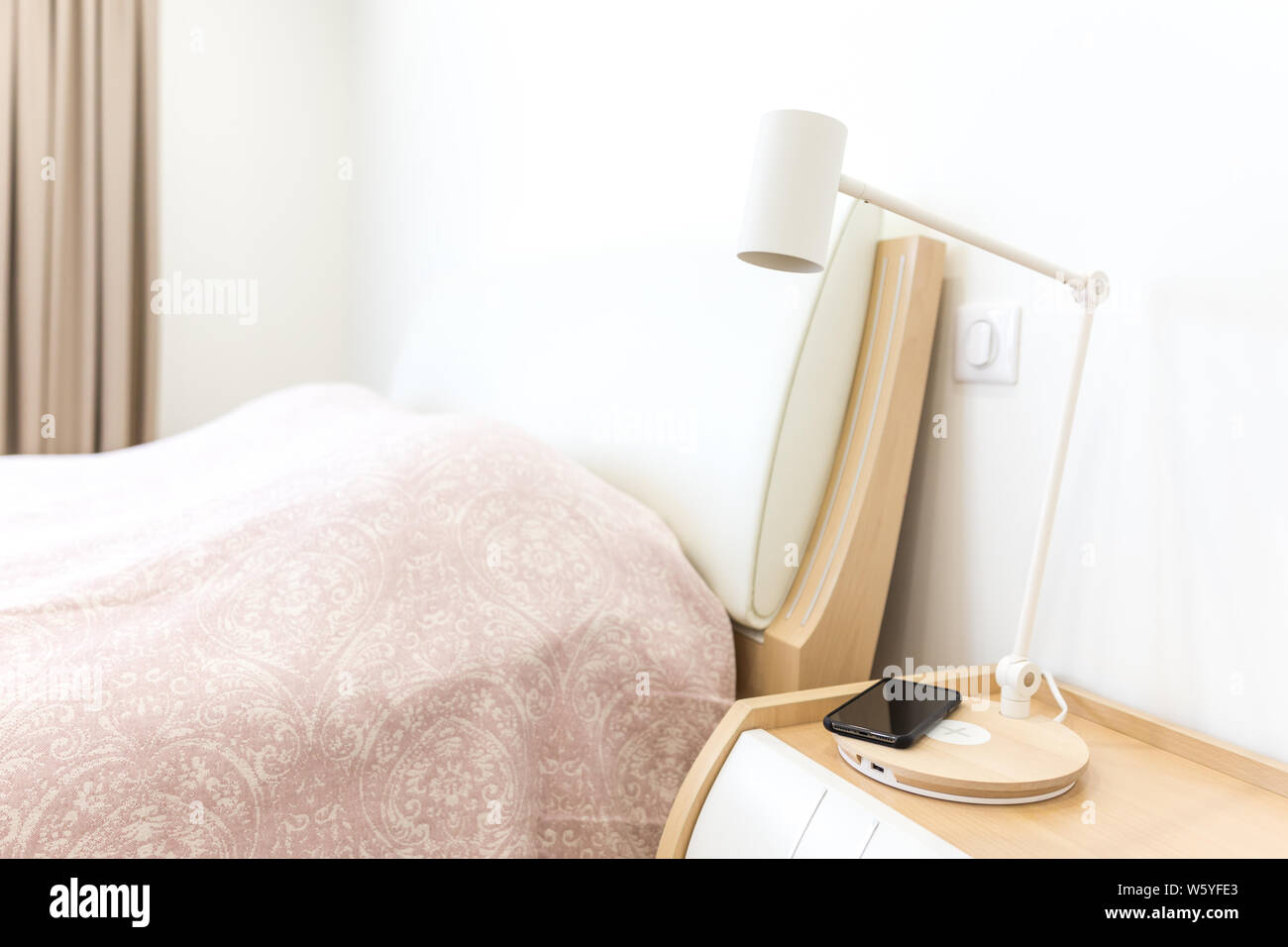 Wireless smartphone charging on lamp near bed Stock Photo Alamy
