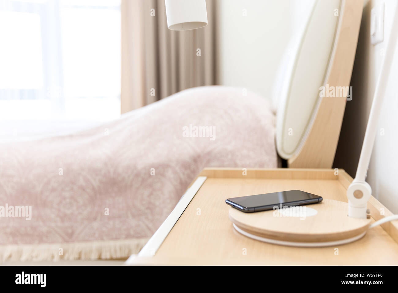 Wireless smartphone charging on lamp near bed Stock Photo Alamy