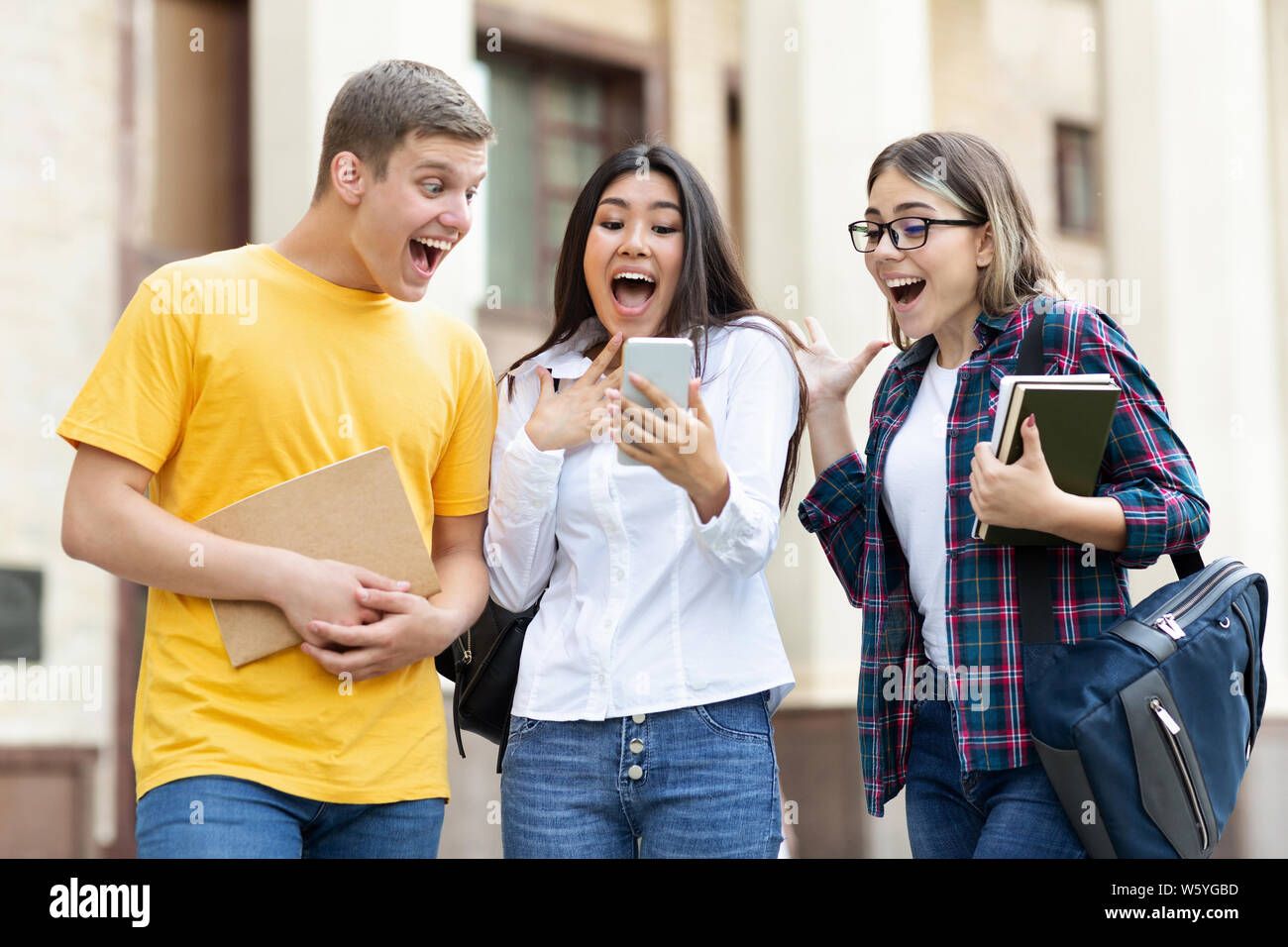 Surprised students checking exam results on smartphone Stock Photo