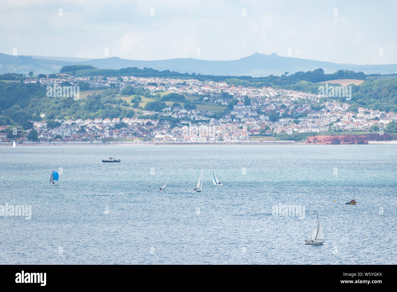View from Berry Head of sailing boats in front of Preston Sands and Marine Parade on the seafront between Paignton and Torquay, with Haytor visible. Stock Photo