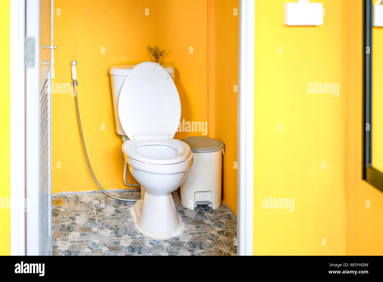 Yellow Toilet room with flush toilet, tash and toilet paper inside it