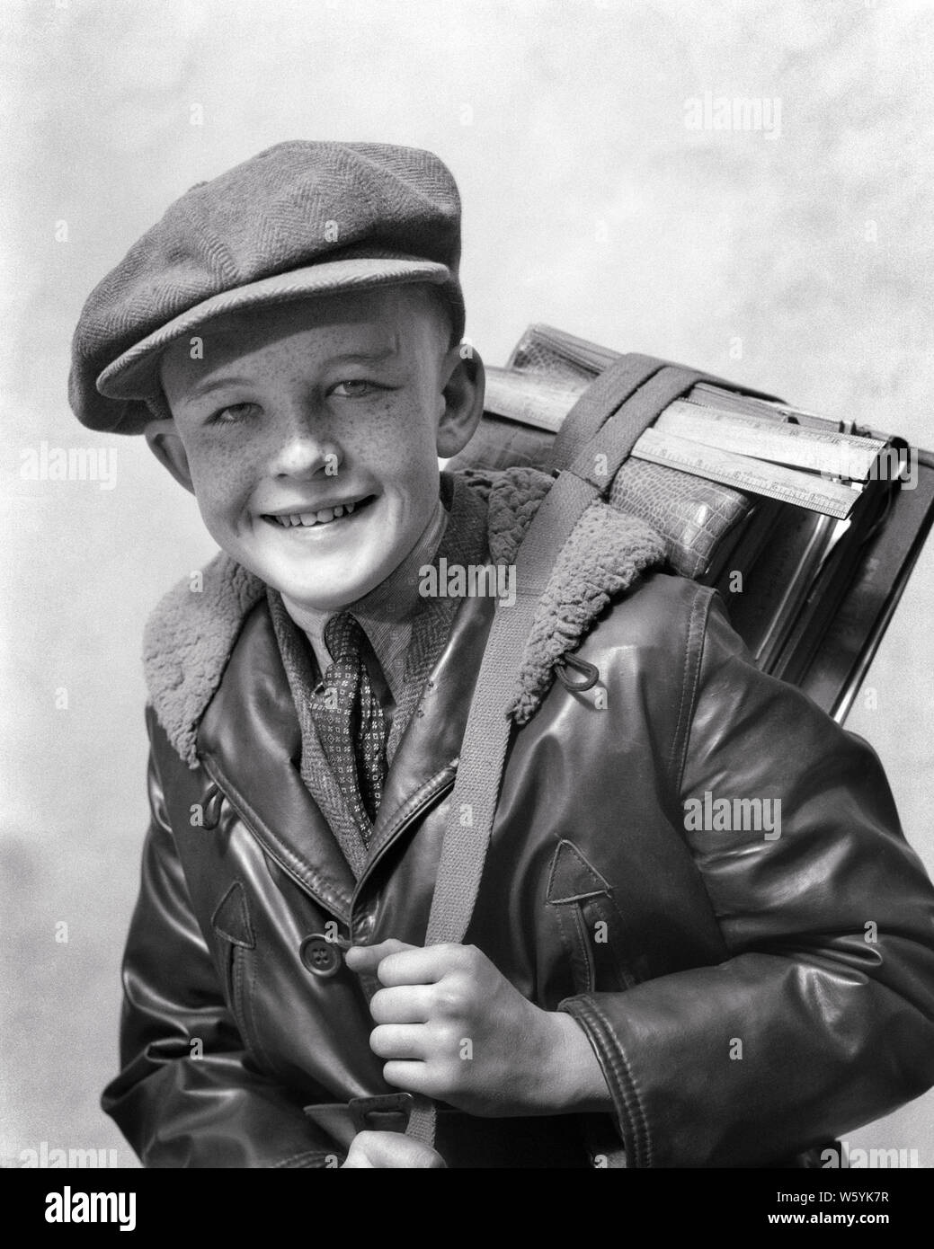 1920s 1930s SMILING PRETEEN BOY WEARING WOOL NEWSBOY CAP LEATHER BOMBER JACKET NECKTIE LOOKING AT CAMERA HOLDING BOOK STRAP - b10161 HAR001 HARS FACIAL BALANCE PLEASED JOY LIFESTYLE SATISFACTION STUDIO SHOT HEALTHINESS UNITED STATES WOOL HALF-LENGTH CLOTH INSPIRATION UNITED STATES OF AMERICA MALES FRECKLES SPIRITUALITY CONFIDENCE EXPRESSIONS B&W EYE CONTACT GOALS SCHOOLS SUCCESS DREAMS GRADE HAPPINESS BRIGHT CHEERFUL STRENGTH COURAGE CHOICE EXCITEMENT INTELLIGENT KNOWLEDGE DIRECTION PRIDE NECKTIE PRETEEN PRIMARY SHARP SMILES CONCEPTUAL IMAGINATION JOYFUL STYLISH NEWSBOY K-12 AGGRESSIVE EAGER Stock Photo