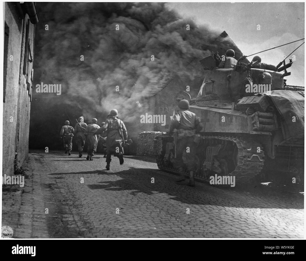 WWII: Europe: Germany; U.S. Third Army iruns throuhg smoke filled streets in Wernberg Stock Photo