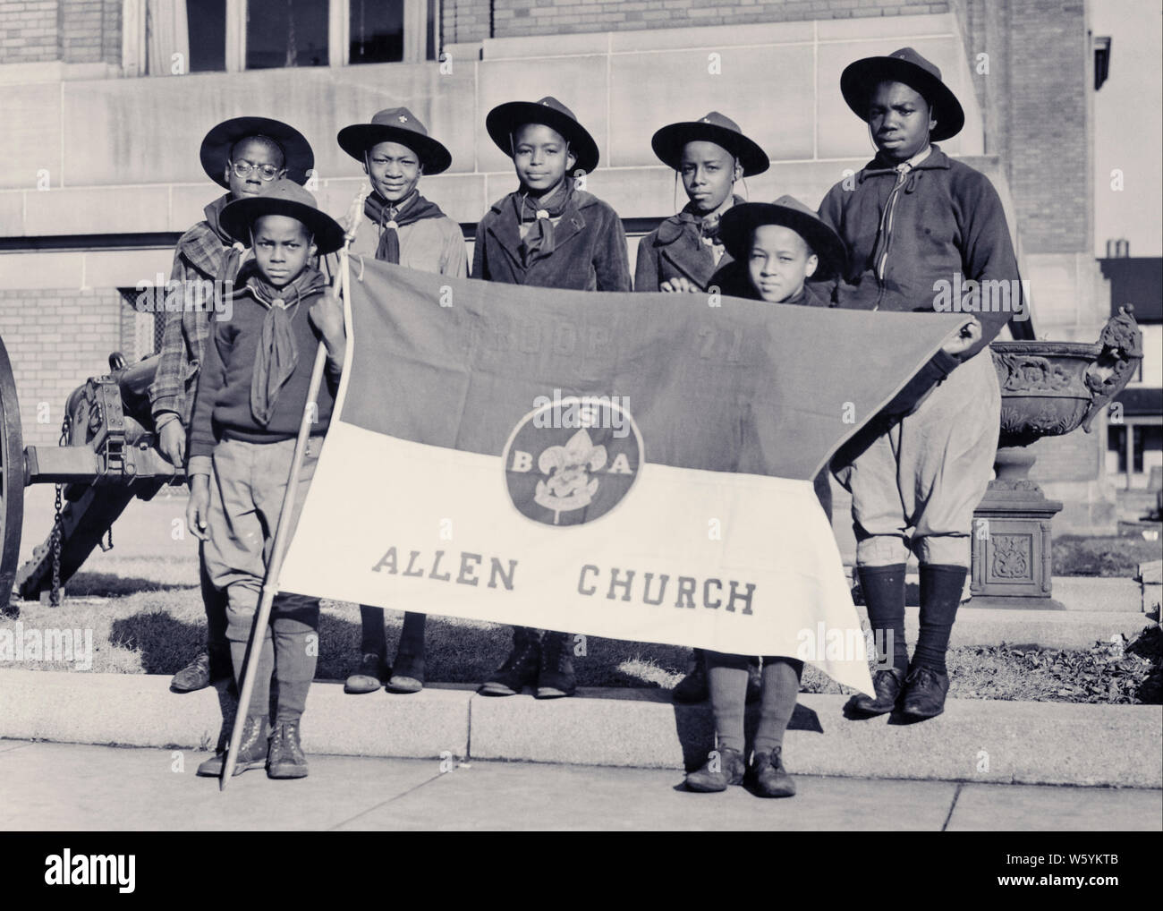 1930s GROUP OF AFRICAN AMERICAN BOY SCOUTS AND MAN LEADER LOOKING AT CAMERA HOLDING UP FLAG WITH BSA INSIGNIA - b3763 HAR001 HARS INSPIRATION SCOUTS MALES CONFIDENCE EXPRESSIONS B&W EYE CONTACT FREEDOM SUCCESS HAPPINESS CHEERFUL ADVENTURE STRENGTH AFRICAN-AMERICANS AFRICAN-AMERICAN RECREATION BLACK ETHNICITY DIRECTION PRIDE OPPORTUNITY OCCUPATIONS BOY SCOUT CONNECTION THRIFTY COURTEOUS FRIENDLY HELPFUL KIND REVERENT STYLISH TRUSTWORTHY GROWTH JUVENILES LOYAL PRE-TEEN PRE-TEEN BOY RELAXATION TOGETHERNESS TROOP YOUNG ADULT MAN BE PREPARED BLACK AND WHITE BRAVE HAR001 OBEDIENT OLD FASHIONED Stock Photo