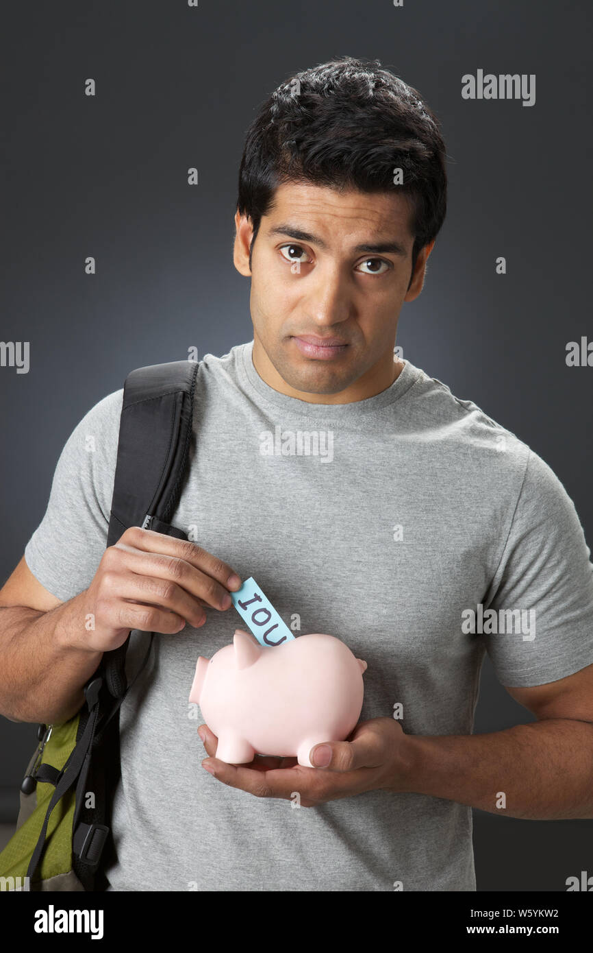 College student putting IOU in piggy bank Stock Photo