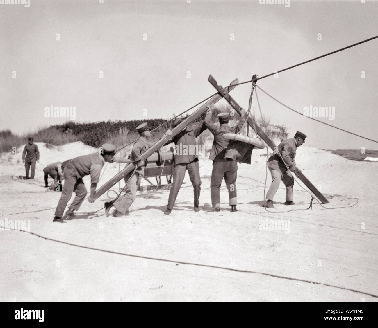 1910s 1920s UNITED STATES COAST GUARD MEN ERECTING BREECHES BUOY LIFE SAVING SYSTEM TO RESCUE PEOPLE FROM WRECKED SHIPS NJ USA - c97 HAR001 HARS FRIENDSHIP FULL-LENGTH PERSONS INSPIRATION UNITED STATES OF AMERICA CARING MALES RISK PROFESSION SHIPS CONFIDENCE TRANSPORTATION B&W LAW ENFORCEMENT NORTH AMERICA NORTH AMERICAN SKILL DISASTER OCCUPATION SKILLS PROTECTION COURAGE CAREERS EXCITEMENT ASSEMBLING PRIDE TO AUTHORITY NJ OCCUPATIONS SAILORS WRECKED CONNECTION CONCEPTUAL SQUAD 1790 1848 ERECTING ESCAPE STYLISH SUPPORT SHIPWRECKED GOVERNMENT AGENCY MARINERS COOPERATION EXTRACT FORMED Stock Photo