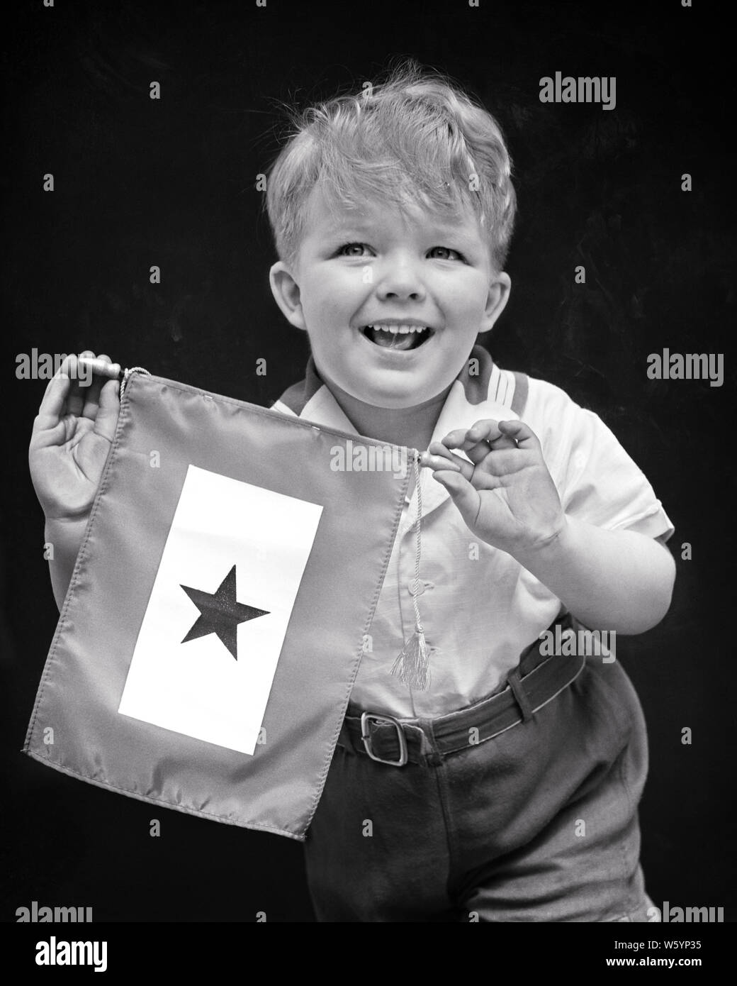 1940s PROUD SMILING BOY RELATIVE HOLDING BLUE STAR SERVICE BANNER INDICATING A FAMILY MEMBER SERVING IN US MILITARY WORLD WAR II - d1665 HAR001 HARS FACIAL COMMUNICATION INFORMATION SONS PLEASED FAMILIES JOY LIFESTYLE HISTORY CELEBRATION PROUD DISPLAY STUDIO SHOT RURAL HOME LIFE UNITED STATES COPY SPACE HALF-LENGTH INSPIRATION UNITED STATES OF AMERICA MALES RISK EXPRESSIONS B&W NORTH AMERICA EYE CONTACT NORTH AMERICAN CHEERFUL STRENGTH COURAGE PRIDE WORLD WAR II IN SMILES UNIFORMS CONCEPTUAL JOYFUL STYLISH FAMILY MEMBERS JUVENILES MEMBER RELATIVE TOGETHERNESS BLACK AND WHITE Stock Photo