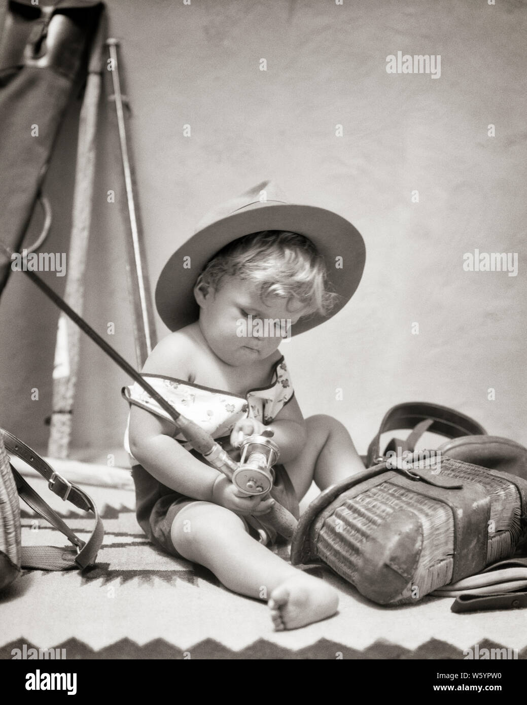 https://c8.alamy.com/comp/W5YPW0/1920s-1930s-engrossed-little-blonde-boy-toddler-wearing-big-hat-sitting-playing-with-fishing-gear-holding-turning-reel-handle-j3746-har001-hars-athletic-rod-bw-turning-dreams-happiness-adventure-discovery-excitement-recreation-reel-engrossed-conceptual-curious-handle-stylish-baby-boy-juveniles-big-hat-black-and-white-caucasian-ethnicity-creel-har001-inquisitive-old-fashioned-W5YPW0.jpg