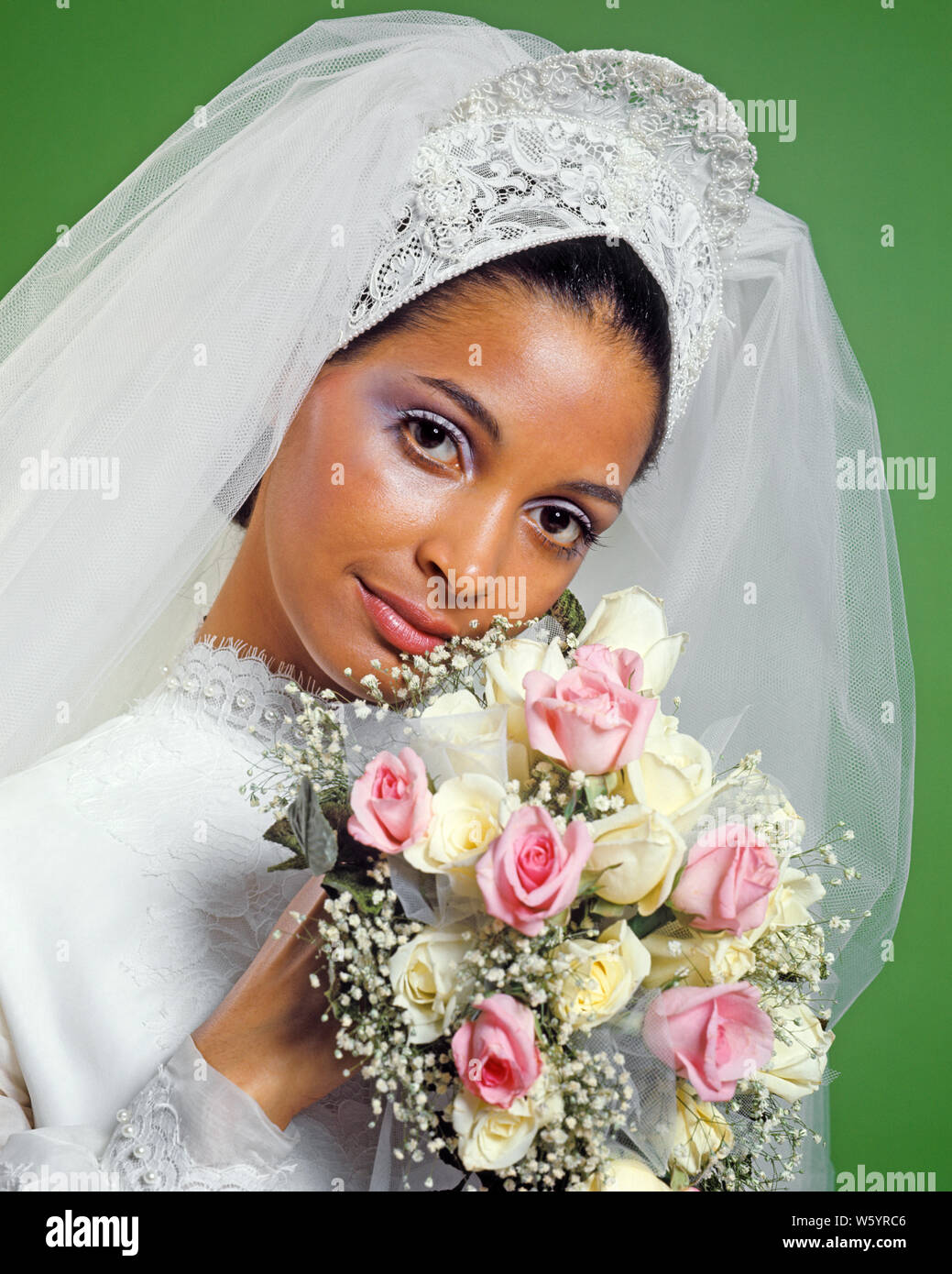 1970s PORTRAIT AFRICAN-AMERICAN BRIDE LACE HEADPIECE VEIL WHITE DRESS BOUQUET WHITE PINK ROSES BABY’S BREATH LOOKING AT CAMERA - kb8742 HAR001 HARS COPY SPACE LADIES MARRIAGE PERSONS VEIL BREATH CONFIDENCE CEREMONY BRIDAL EYE CONTACT DREAMS HAPPINESS HEAD AND SHOULDERS CHEERFUL BRIDES CUSTOM AFRICAN-AMERICANS AFRICAN-AMERICAN TRADITION NUPTIAL NUPTIALS OCCASION BLACK ETHNICITY MARRYING PRIDE SMILES HEADPIECE JOYFUL RITE OF PASSAGE STYLISH BABY'S WED MARRY MATRIMONY YOUNG ADULT WOMAN HAR001 OLD FASHIONED AFRICAN AMERICANS Stock Photo
