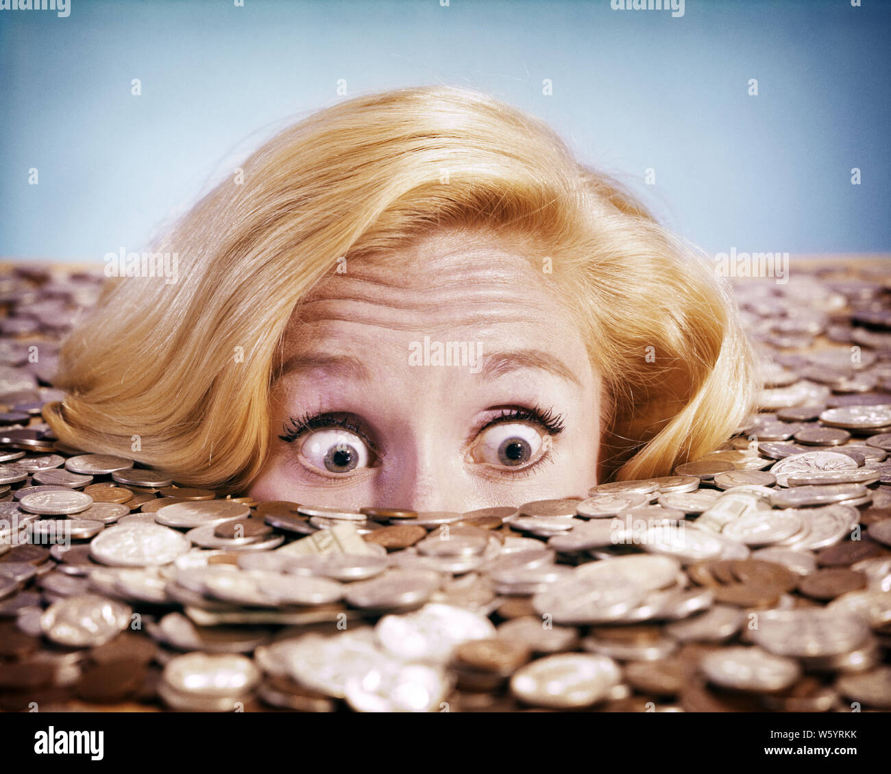 1960s PANICKED BUG-EYED BLOND YOUNG WOMAN BURIED UP TO HER NOSE IN PILE OF COINS AND CURRENCY - kg2623 HAR001 HARS FEMALES CURRENCY TREASURE STUDIO SHOT PORTRAITS GROWNUP COPY SPACE PERSONS GROWN-UP DROWNING BURIED EYE CONTACT BIZARRE SUCCESS LUCK BUG-EYED PEERING WEIRD HEAD AND SHOULDERS OVERWHELMED AND GROTESQUE WEALTH ZANY UNCONVENTIONAL UP INUNDATED PEEPING CONCEPTUAL INUNDATION WACKY WIDE EYED IDIOSYNCRATIC INUNDATE PANICKED AMUSING ECCENTRIC OVERWHELMING PEOPLE ADULTS REWARD STARTLED YOUNG ADULT WOMAN CAUCASIAN ETHNICITY ERRATIC HAR001 OLD FASHIONED OUTRAGEOUS SUDDEN Stock Photo