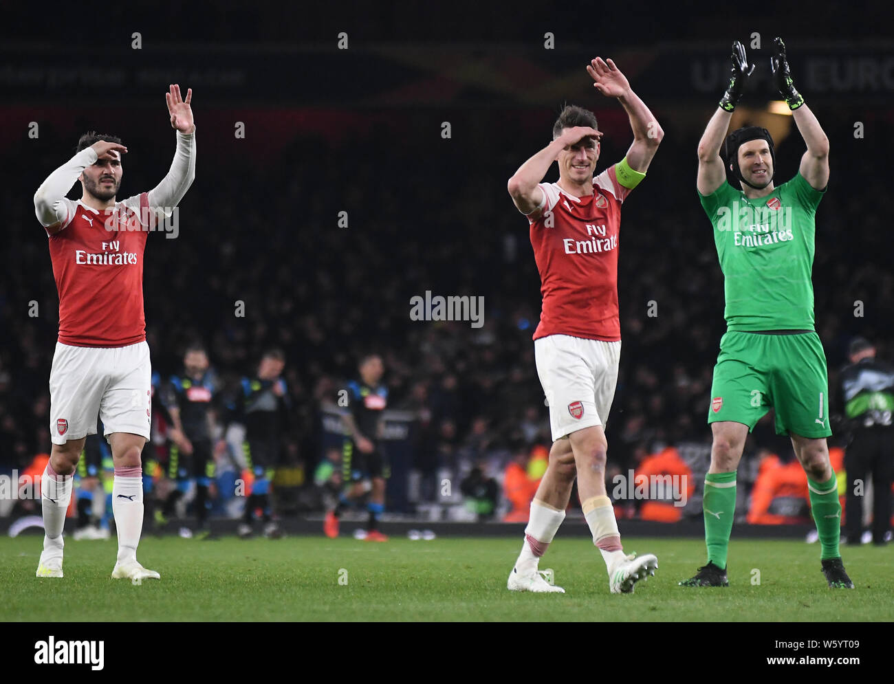 LONDON, ENGLAND - APRIL 11, 2019: Sead Kolasinac of Arsenal, Laurent Koscielny of Arsenal and Petr Cech of Arsenal salute the fans after the first leg of the 2018/19 UEFA Europa League Quarter-finals game between Arsenal FC (England) and SSC Napoli (Italy) at Emirates Stadium. Stock Photo