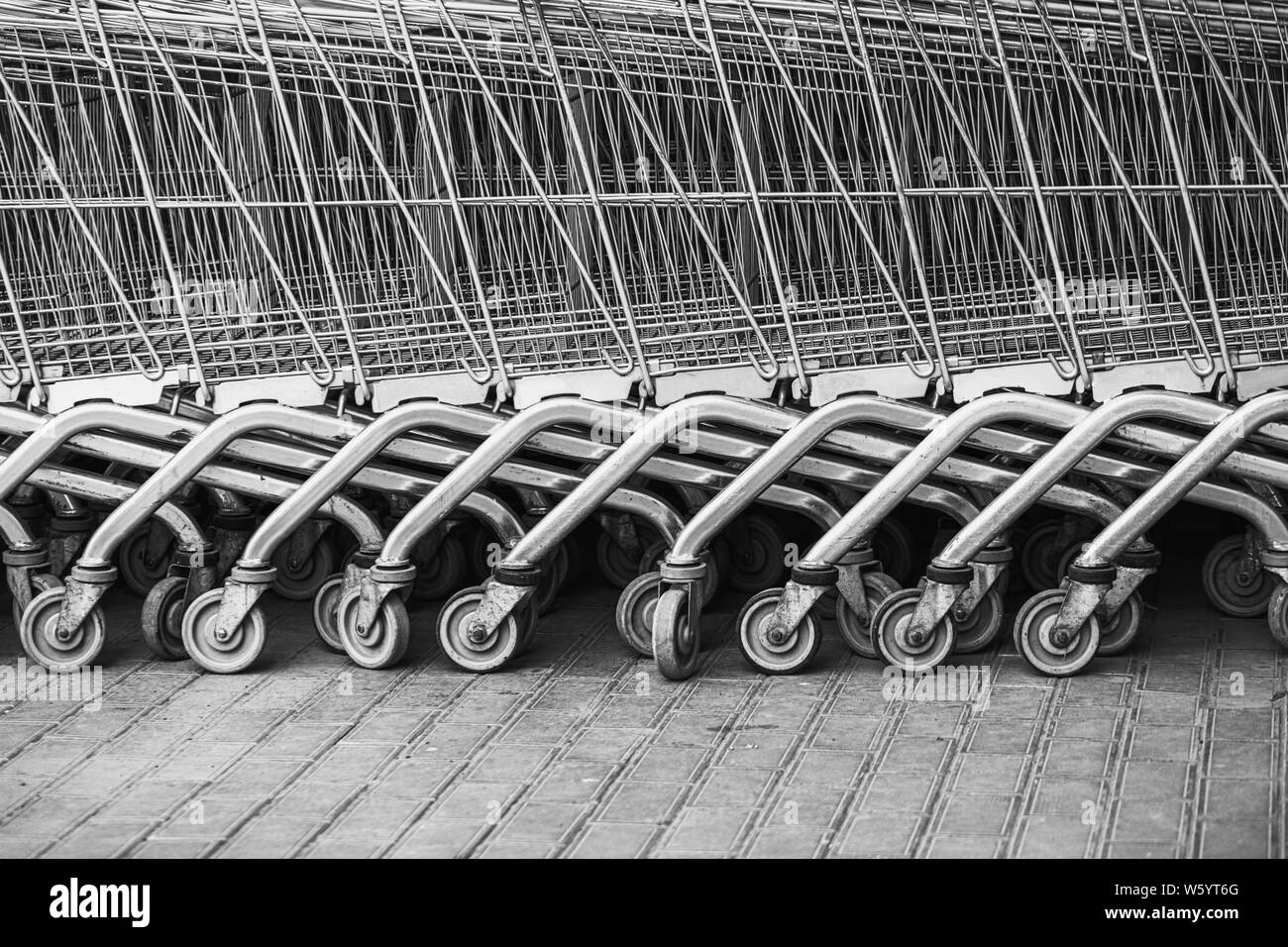 Shopping carts arranged in a row on the street near the supermarket.Close up wheel of shopping cart. Concept of shopping. Selective focus. Stock Photo