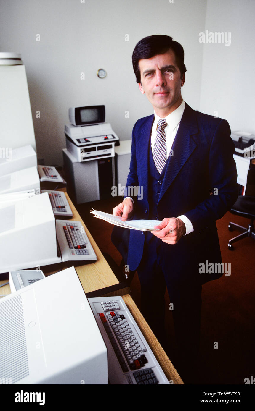 1980s MAN COMPUTER SYSTEMS SALESMAN STANDING LOOKING AT CAMERA IN A ROOM WITH EARLY HARDWARE MONITORS AND KEYBOARDS - ko1299 PHT001 HARS COMMUNICATING UNITED STATES COPY SPACE HALF-LENGTH COMPUTERS PERSONS GROWN-UP MALES CONFIDENCE EXPRESSIONS SCREENS NORTH AMERICA WORK PLACE EYE CONTACT NORTH AMERICAN SUIT AND TIE SELLING EARLY NETWORKING MONITORS INNOVATION PRIDE OPPORTUNITY AUTHORITY OCCUPATIONS HIGH TECH CONNECTION ELECTRIC APPLIANCE HARDWARE STYLISH TEXAS INSTRUMENTS COMMUNICATE HIGH-TECH KEYBOARDS MID-ADULT MID-ADULT MAN PROGRAMMER SALESMEN CAUCASIAN ETHNICITY OLD FASHIONED Stock Photo