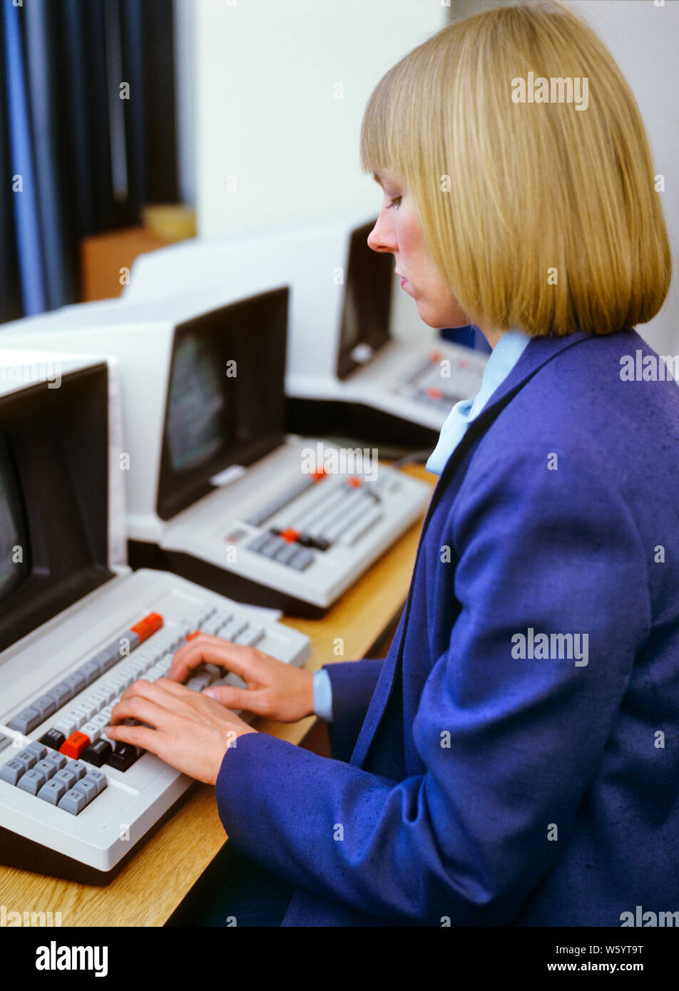 1980s BLOND WOMAN WEARING BLUE SUIT WORKING SITTING AT COMPUTER TERMINAL TYPING HANDS ON KEYBOARD - ko1301 PHT001 HARS HISTORY FEMALES JOBS UNITED STATES COPY SPACE HALF-LENGTH LADIES COMPUTERS PERSONS UNITED STATES OF AMERICA CONFIDENCE BUSINESSWOMAN NORTH AMERICA NORTH AMERICAN SKILL OCCUPATION SKILLS HIGH ANGLE EARLY TYPING NETWORKING HAIRSTYLE PROGRESS OPPORTUNITY NYC OCCUPATIONS HIGH TECH CONNECTION HARDWARE NEW YORK CITIES STYLISH BUSINESSWOMEN NEW YORK CITY TEXAS INSTRUMENTS BOB HIGH-TECH MID-ADULT MID-ADULT MAN MID-ADULT WOMAN PAGEBOY TERMINAL CAUCASIAN ETHNICITY OLD FASHIONED Stock Photo