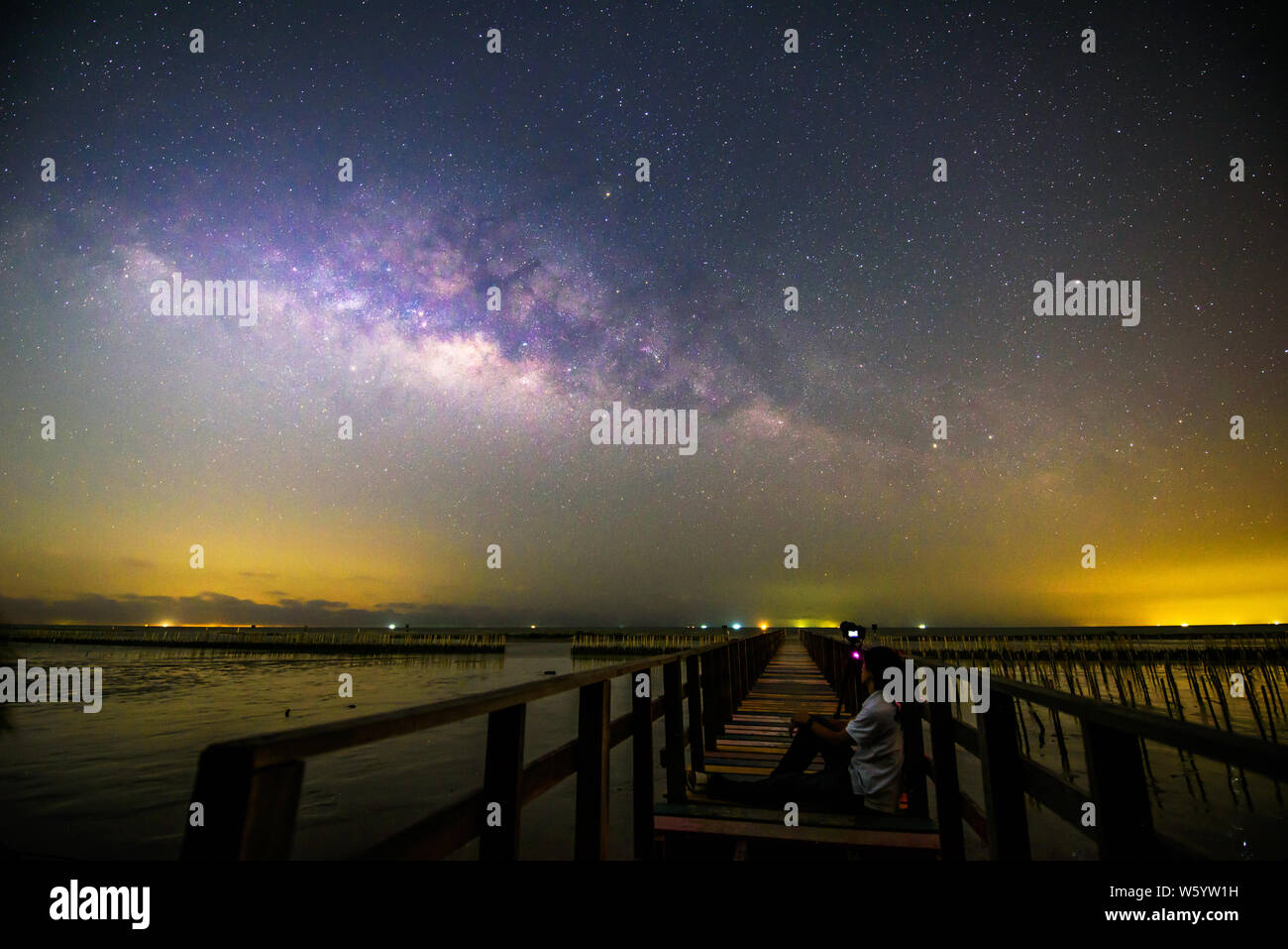 milky way with the man sitting at the bridge Stock Photo