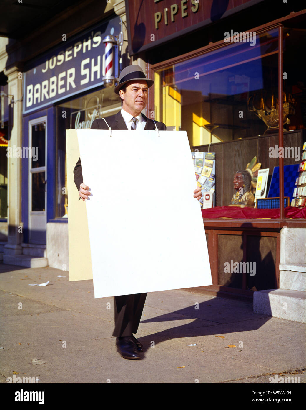 1960s 1950s SMILING MAN WALKING IN SUIT TIE AND HAT CARRYING A SANDWICH BOARD - ks4627 HAR001 HARS COMMUNICATION ADVERTISING COMPETITION INFORMATION PROTEST LIFESTYLE PORTRAITS COPY SPACE FULL-LENGTH PERSONS SHOPS INSPIRATION CONFIDENCE SUIT AND TIE OCCUPATION STRATEGY CUSTOMER SERVICE AND NETWORKING INNOVATION OPPORTUNITY NECKTIE OCCUPATIONS POSING SMILES STORES BRICK WALL CONCEPTUAL SANDWICH BOARD ANNOUNCEMENT DAYTIME PROTESTING PROMOTION STORE FRONTS SYMBOLIC BARBER SHOP COMMERCE CREATIVITY MID-ADULT MID-ADULT MAN ANNOUNCING BUSINESSES CAUCASIAN ETHNICITY HAR001 MESSAGE OLD FASHIONED Stock Photo