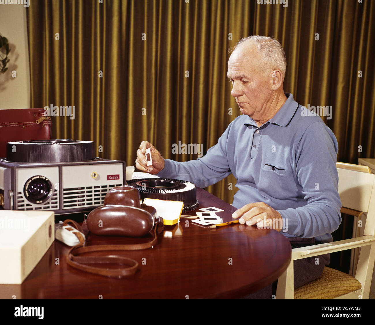 1960s SENIOR MAN AT HOME VIEWING EDITING FAMILY VACATION 35MM PHOTO SLIDES BESIDE CAMERA AND PROJECTOR - ks5139 HAR001 HARS ELDER HEALTHINESS HOME LIFE COPY SPACE HALF-LENGTH PERSONS INSPIRATION CAMERAS CARING MALES SENIOR MAN SENIOR ADULT SENIOR WOMAN SUCCESS TIME OFF SKILL ACTIVITY AMUSEMENT DREAMS PROJECTOR HAPPINESS OLDSTERS OLDSTER DISCOVERY HOBBY LEISURE TRIP INTEREST AND GETAWAY CHOICE EXCITEMENT HOBBIES KNOWLEDGE RECREATION CAROUSEL PASTIME PRIDE PLEASURE HOLIDAYS ELDERS SLIDES CONNECTION REVIEWING CONCEPTUAL BESIDE PHOTOGRAPHY STYLISH VIEWER 35MM ELDERLY MAN CREATIVITY ELECTRONIC Stock Photo