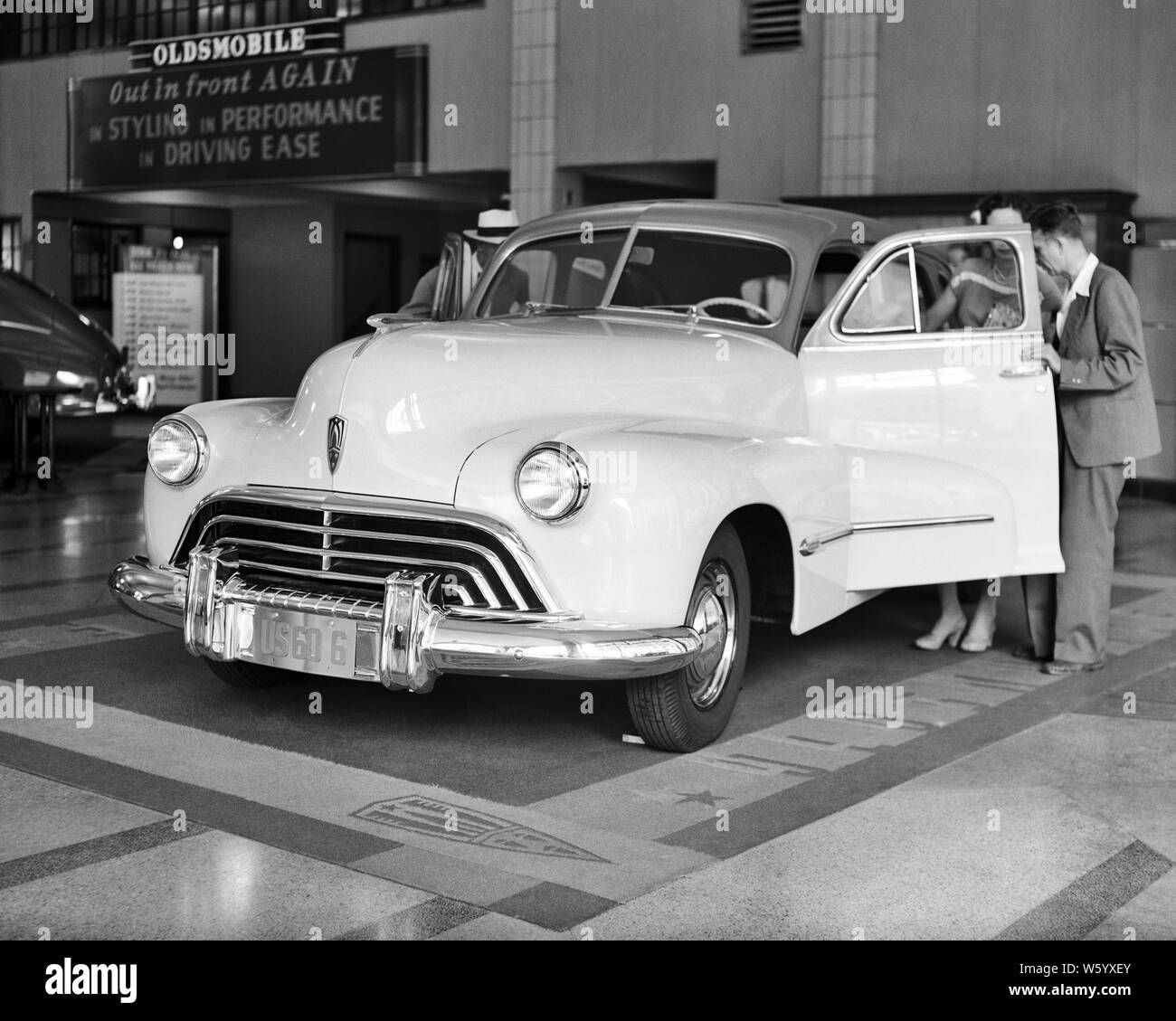 1940s COUPLE LOOKING AT NEW CAR 1946 MODEL AT OLDSMOBILE AUTO DEALERSHIP AT 1730 BROADWAY NYC - q45318 CPC001 HARS SHOWROOM LIFESTYLE FEMALES MARRIED DECISION SPOUSE HUSBANDS LUXURY UNITED STATES COPY SPACE LADIES DEALERSHIP PERSONS UNITED STATES OF AMERICA AUTOMOBILE MALES DEALER TRANSPORTATION B&W PARTNER SHOPPER GOALS SHOPPERS TEMPTATION CUSTOMER SERVICE AUTOS OLDSMOBILE CHOICE PROGRESS INNOVATION OPPORTUNITY NYC PURCHASE CONCEPTUAL NEW YORK AUTOMOBILES CITIES STYLISH VEHICLES 1946 NEW YORK CITY NEW CAR BROADWAY COOPERATION WIVES BLACK AND WHITE CAUCASIAN ETHNICITY OLD FASHIONED Stock Photo