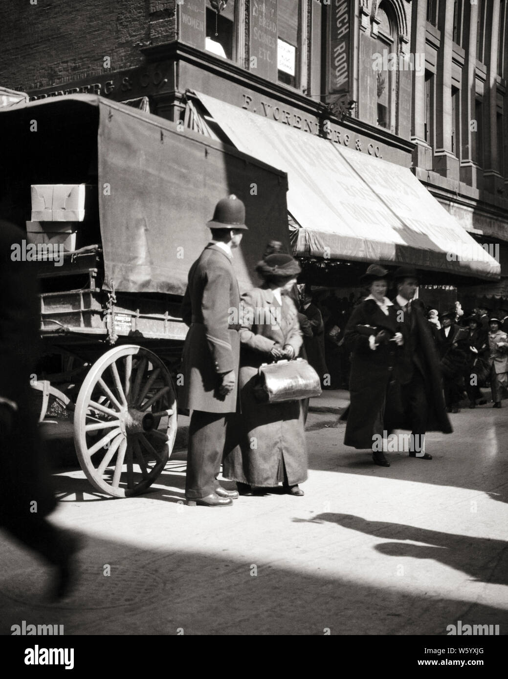 1900s TURN OF THE 20TH CENTURY MAN POLICE OFFICER HELPING SENIOR WOMAN PEDESTRIAN WALKING THROUGH STREET TRAFFIC BOSTON MA USA - q74191 CPC001 HARS OLD TIME NOSTALGIA OLD FASHION 1 POLICEMAN WAGON THROUGH CAREER SECURITY SAFETY BOSTON MYSTERY ABSTRACT LIFESTYLE ARCHITECTURE ELDER FEMALES JOBS UNITED STATES COPY SPACE FULL-LENGTH LADIES PERSONS INSPIRATION UNITED STATES OF AMERICA MALES RISK OFFICER BUILDINGS PROFESSION B&W NORTH AMERICA COP MASSACHUSETTS PROTECT AND SERVE NORTH AMERICAN SKILL OCCUPATION PEDESTRIAN SKILLS OLD AGE OLDSTERS OLDSTER EARLY PROPERTY PROTECTION Stock Photo