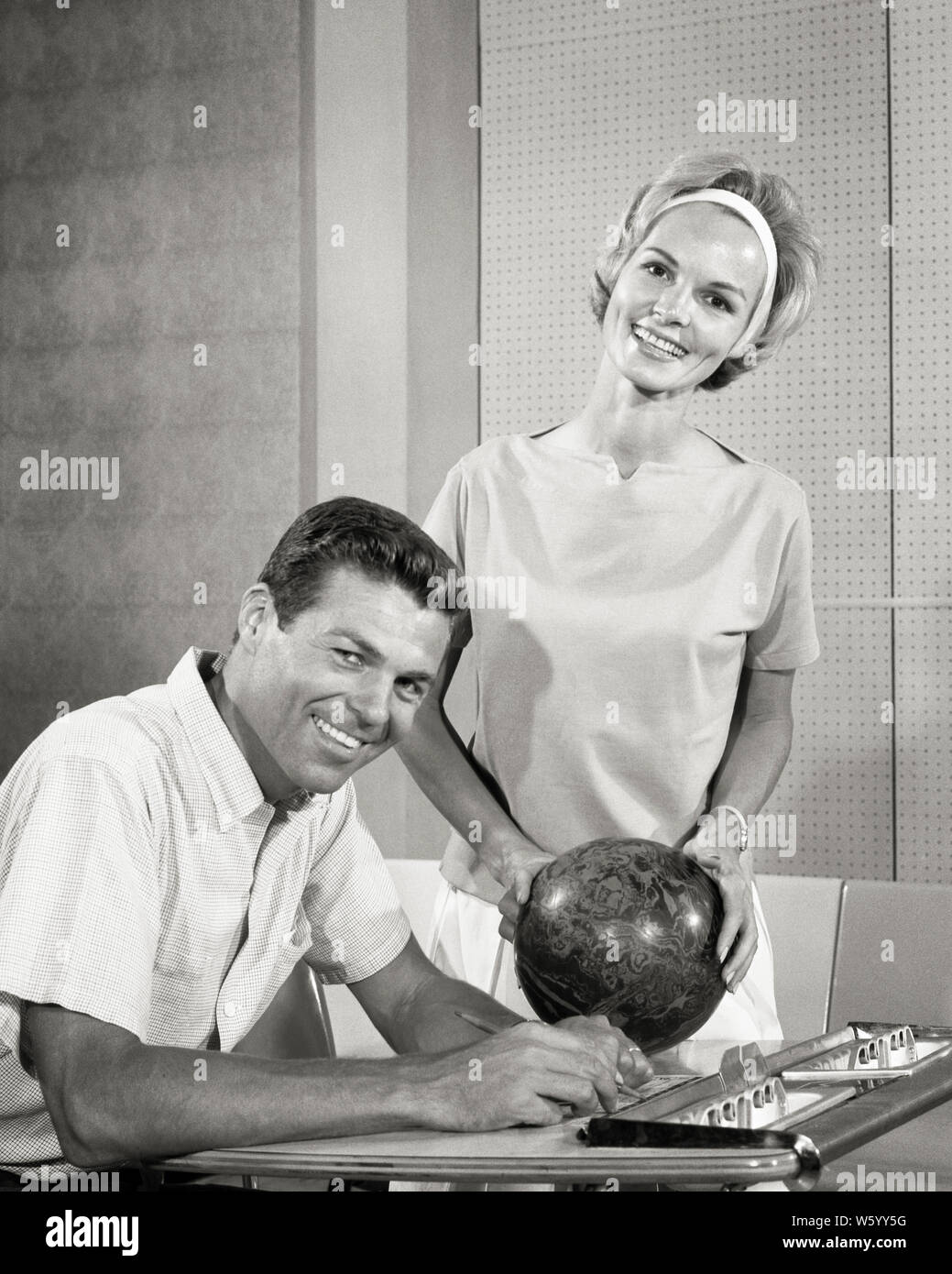 1960s SMILING COUPLE MAN KEEPING SCORE AND WOMAN HOLDING BOWLING BALL BOTH LOOKING AT CAMERA - s12814 HAR001 HARS TEAMWORK COMPETITION INFORMATION SCORE ATHLETE PLEASED JOY LIFESTYLE SATISFACTION FEMALES MARRIED SPOUSE HUSBANDS BOWLER HEALTHINESS COPY SPACE FRIENDSHIP HALF-LENGTH LADIES PERSONS MALES ATHLETIC CONFIDENCE B&W LANE PARTNER EYE CONTACT DATING ACTIVITY HAPPINESS PHYSICAL BOWLING BALL CHEERFUL LEISURE STRENGTH AND EXCITEMENT RECREATION ATTRACTION SMILES COURTSHIP FLEXIBILITY JOYFUL MUSCLES STYLISH POSSIBILITY COOPERATION KEEPING MID-ADULT RELAXATION SOCIAL ACTIVITY TOGETHERNESS Stock Photo
