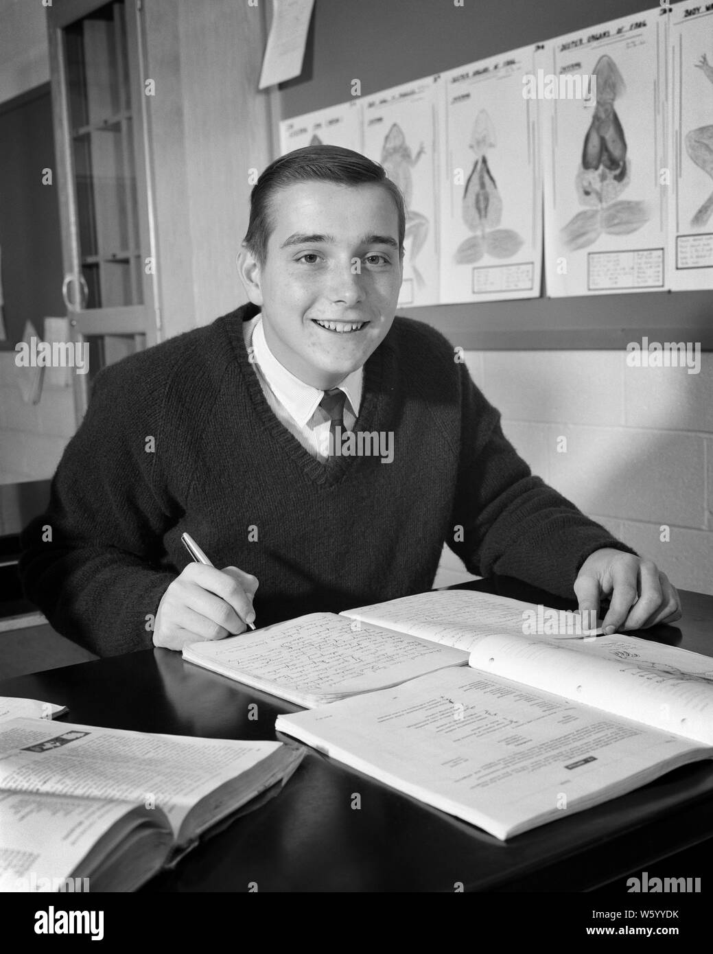 1960s SMILING BOY STUDENT IN BIOLOGY CLASS READING  BOOK TAKE NOTES  IN NOTEBOOK - s15401 HAR001 HARS INFORMATION PLEASED JOY LIFESTYLE COPY SPACE HALF-LENGTH PERSONS INSPIRATION BIOLOGY MALES TEENAGE BOY CONFIDENCE EXPRESSIONS B&W EYE CONTACT SUCCESS HAPPINESS CHEERFUL DISCOVERY STRENGTH EXCITEMENT KNOWLEDGE PROGRESS DIRECTION PRIDE IN OPPORTUNITY HIGH SCHOOL SMILES HIGH SCHOOLS CONCEPTUAL STILL LIFE TAKING NOTES INVOLVED JOYFUL STYLISH TEENAGED EAGER GROWTH JUVENILES BLACK AND WHITE CAUCASIAN ETHNICITY HAR001 OLD FASHIONED Stock Photo