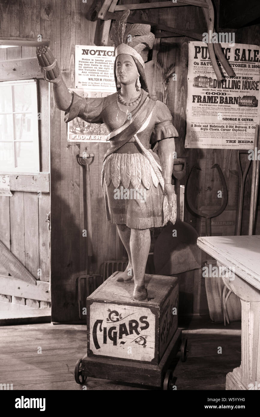 1950s 1960s 1970s ANTIQUE CIGAR STORE INDIAN CARVED WOOD STATUE OF A NATIVE AMERICAN WOMAN HOLDING UP A BUNDLE OF TOBACCO CIGARS - s15949 HAR001 HARS B&W NORTH AMERICA ADVERTISEMENT SCULPTURE TOBACCO CIGARS VALUABLE A AN OF UP CARVED PAINTED CONCEPT CONCEPTUAL STILL LIFE COLLECTABLE STOREFRONT WHEELED NATIVE AMERICAN NOBLE SAVAGE BUNDLE INDIAN PRINCESS OFFENSIVE PROMOTION SYMBOLIC CARICATURE CONCEPTS MOVABLE NATIVE AMERICANS SIDEWALK-OBSTRUCTION STEREOTYPE TOBACCO SHOP TOBACCONIST WOODEN INDIAN BLACK AND WHITE FOLK ART HAR001 INDIGENOUS OLD FASHIONED REPRESENTATION Stock Photo