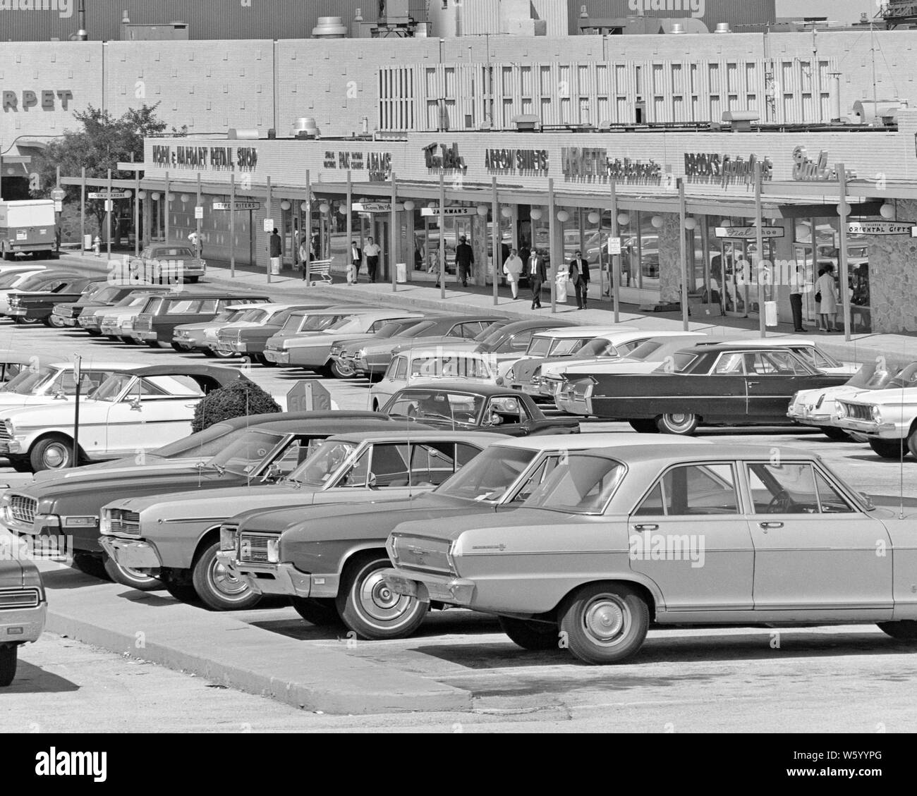 1970s VARIETY OF CARS JAM PACKED IN SHOPPING CENTER STRIP MALL PARKING LOT PEDESTRIANS AND SHOPPERS WALKING BY STORE FRONTS - s17107 HAR001 HARS VARIETY VEHICLES GROCERY STORE SHOPPING CENTER STORE FRONTS STRIP MALL GROWTH HAIR SALON PET STORE TOY STORE BLACK AND WHITE HAR001 OLD FASHIONED PARKING LOT Stock Photo