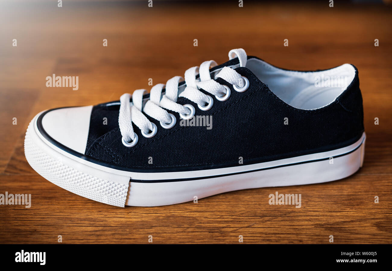 Simple classic black sneakers with white shoelace Stock Photo - Alamy