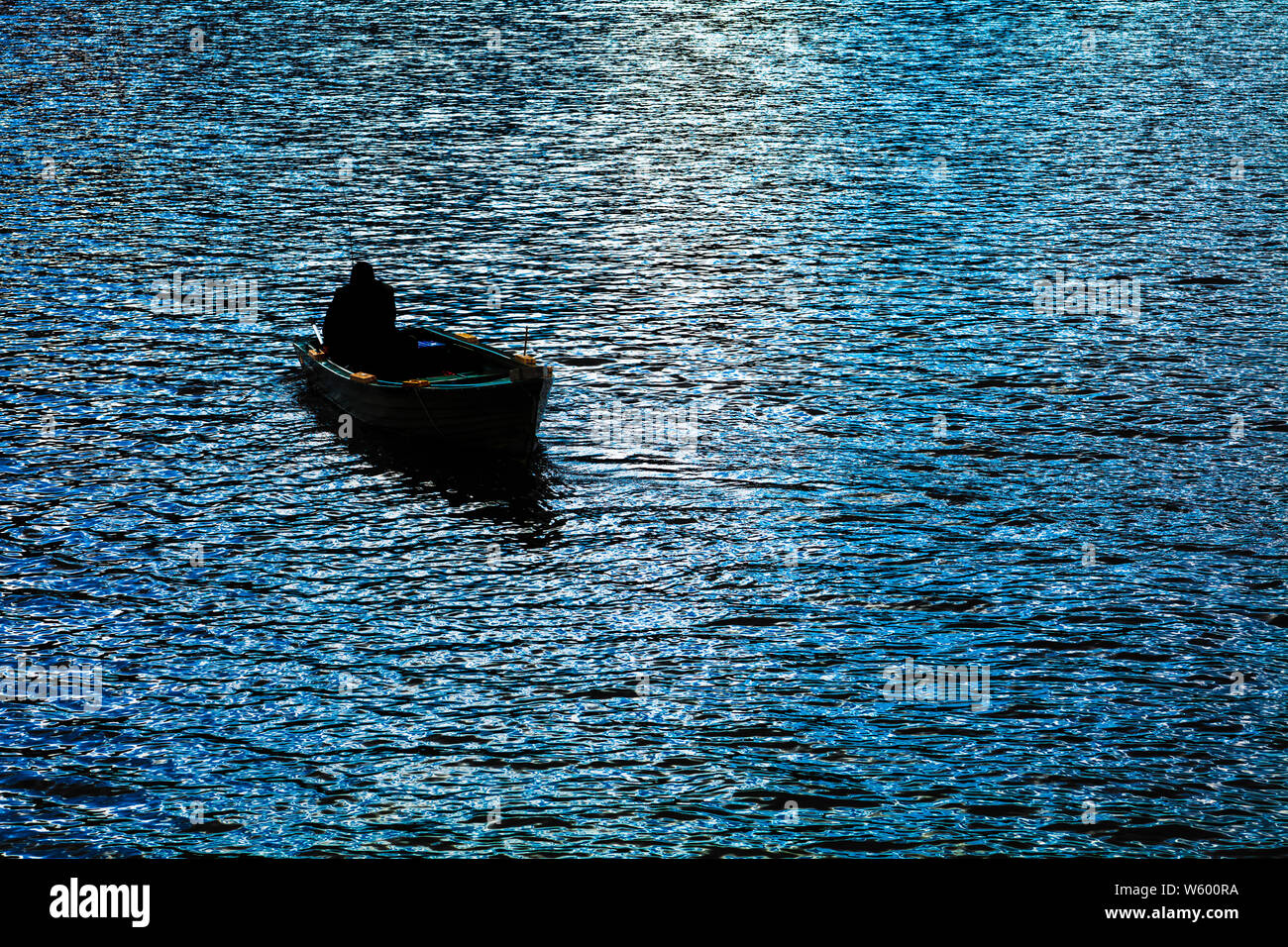 Fisherman in small boat silhouette Stock Photo - Alamy
