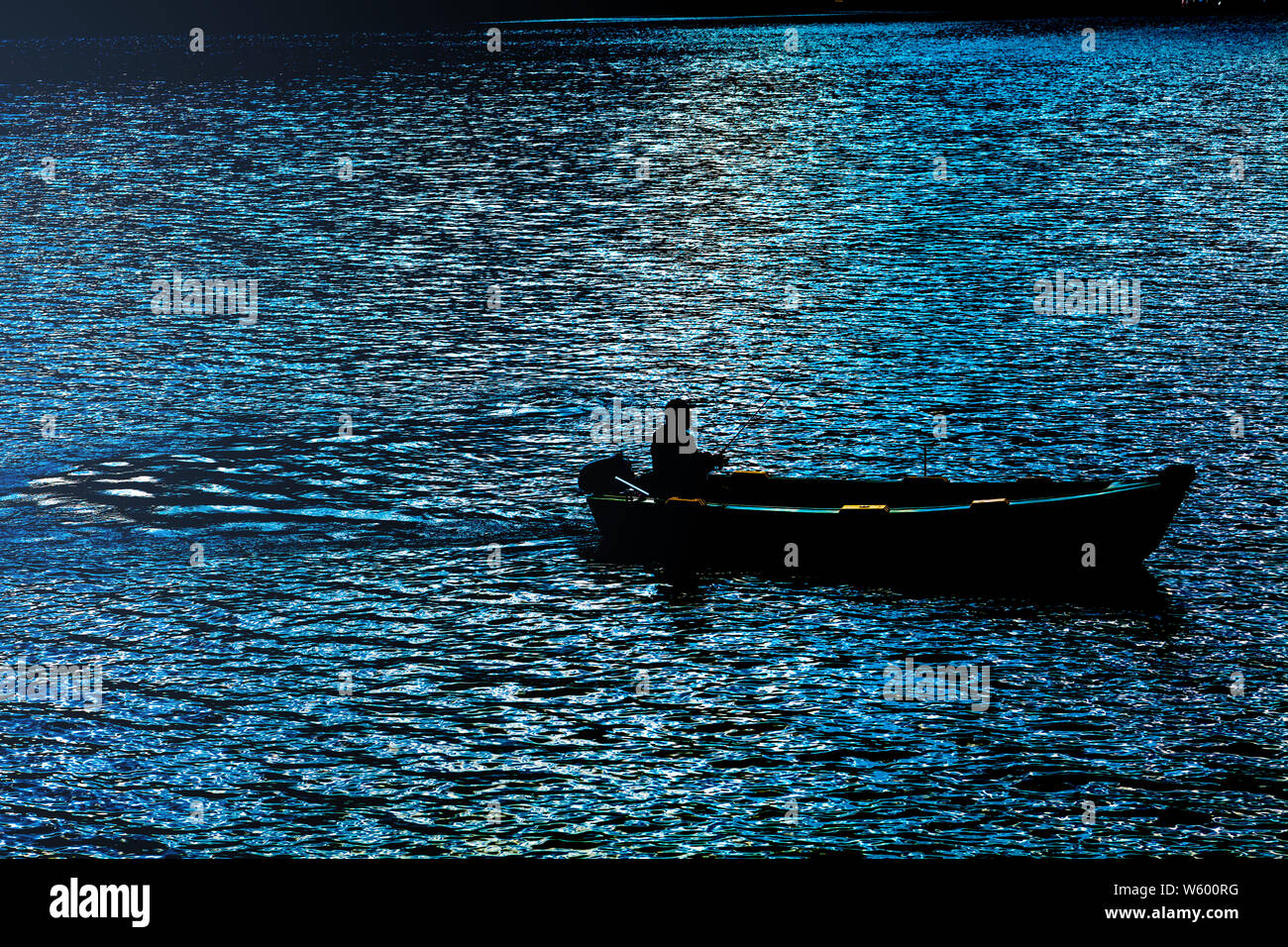 Fisherman in small boat silhouette Stock Photo - Alamy