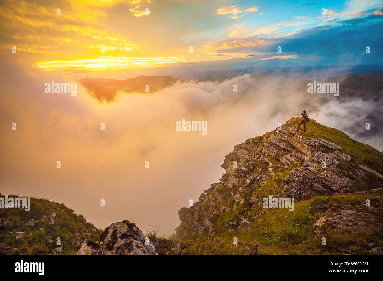 Photographer on top of steep rocks photographing the sunset above the ...