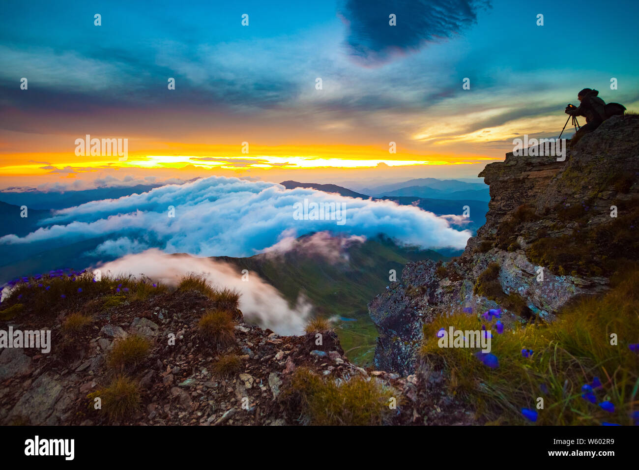 Photographer on top of steep rocks photographing the sunset above the ...