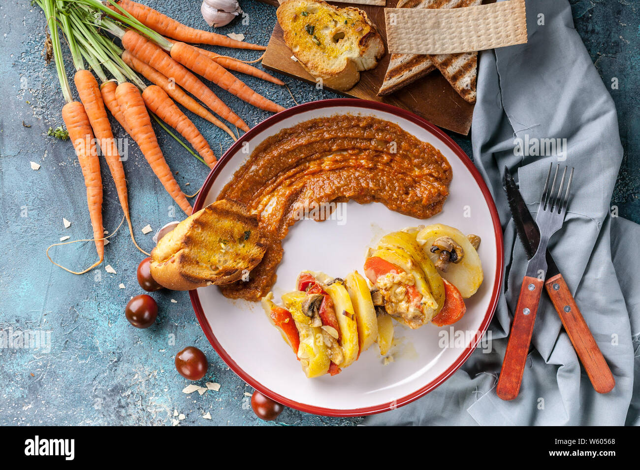 Vegetarian food. Stewed potatoes with zucchini, carrots, mushrooms and cheese. Carrot mash with champignons. Top view Stock Photo
