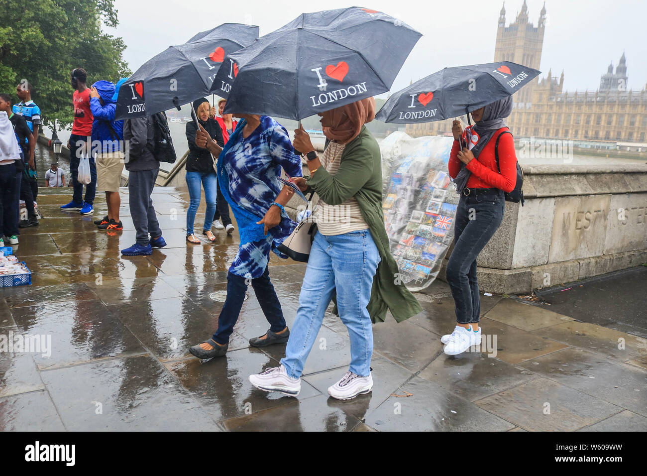 Tourists on Westminster Bridge with souvenir umbrellas during rain
